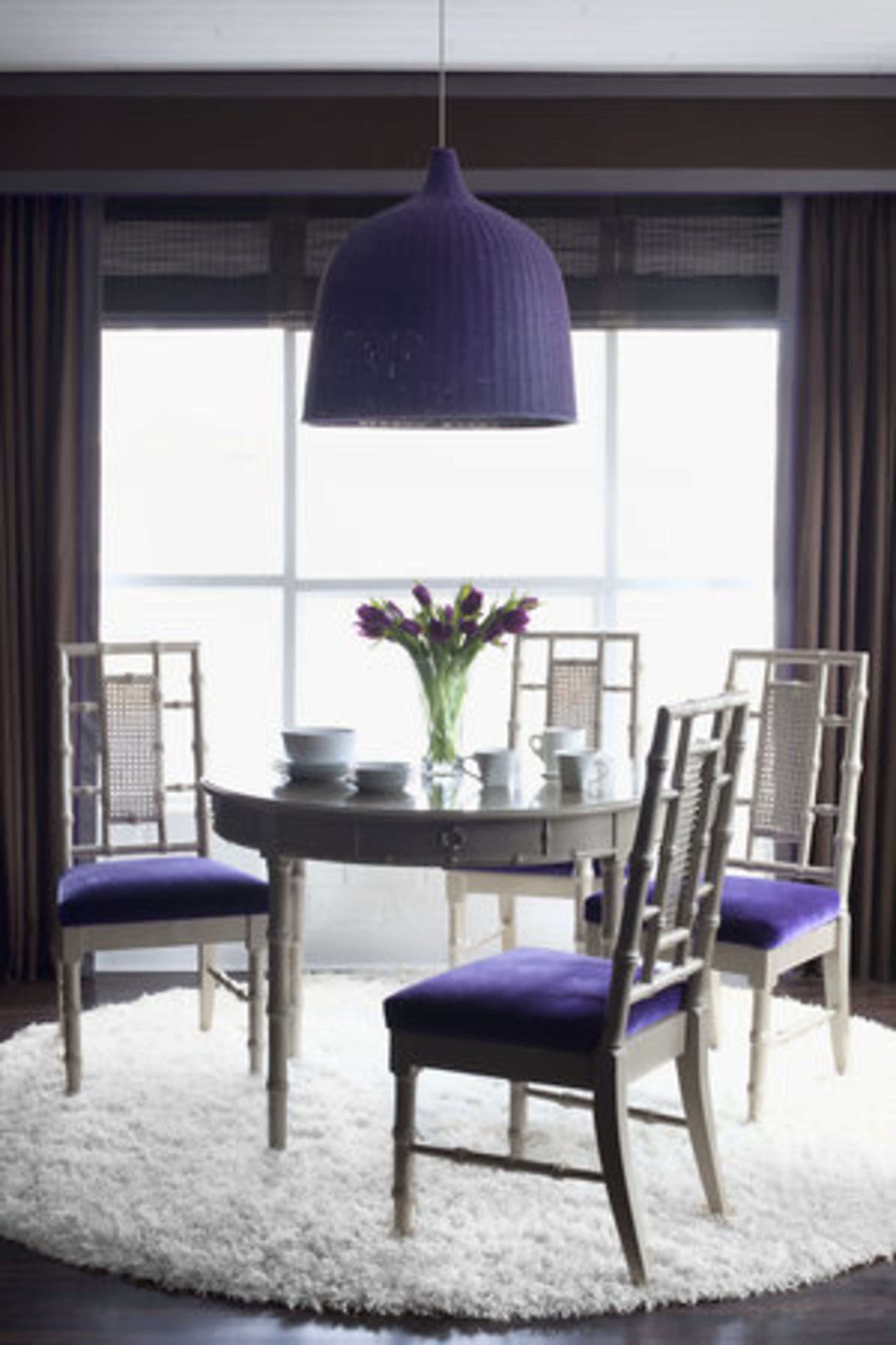 Flynn abhors matching furniture sets, unless they are vintage like this Seventies dining set repainted in glossy white, reupholstered and perfectly accented with an Ikea pendant lamp painted a coordinating violet.