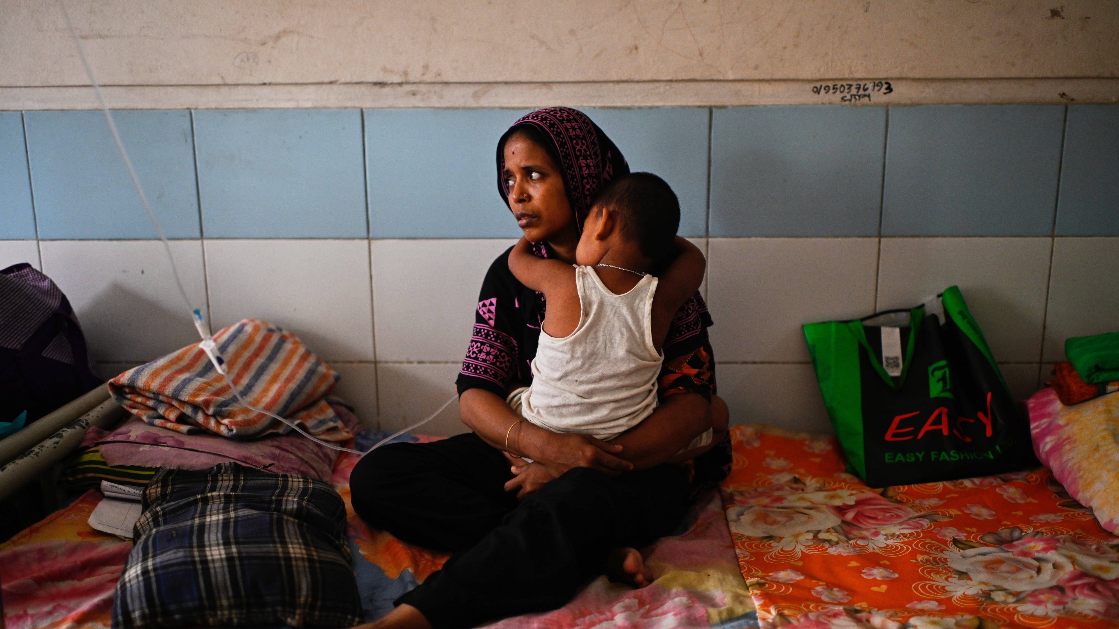 A woman takes care of her child while getting treatment for measles during the outbreak, in a hospital in Dhaka, Bangladesh, Tuesday, Sept. 8, 2026. (AP Photo/Mahmud Hossain Opu)