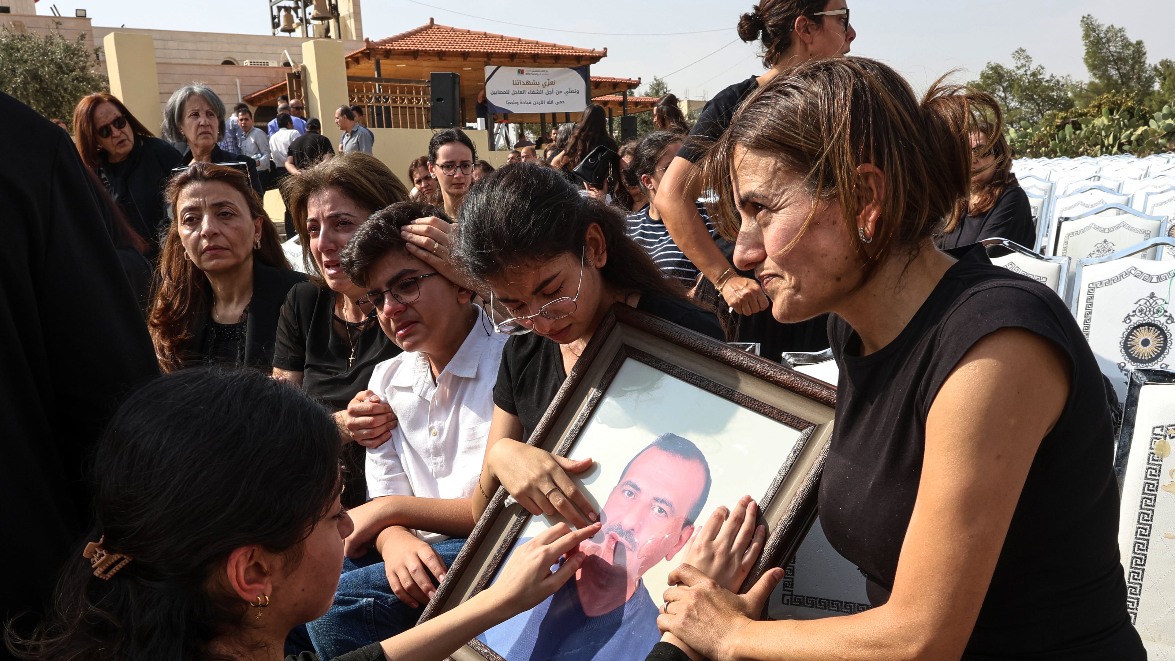 Relatives mourn as they hold a framed portrait of a victim killed in an attack on a Greek Orthodox church during a funeral ceremony in Karak, Jordan, Sunday, Oct. 25, 2026. (AP Photo/Raad Adayleh)