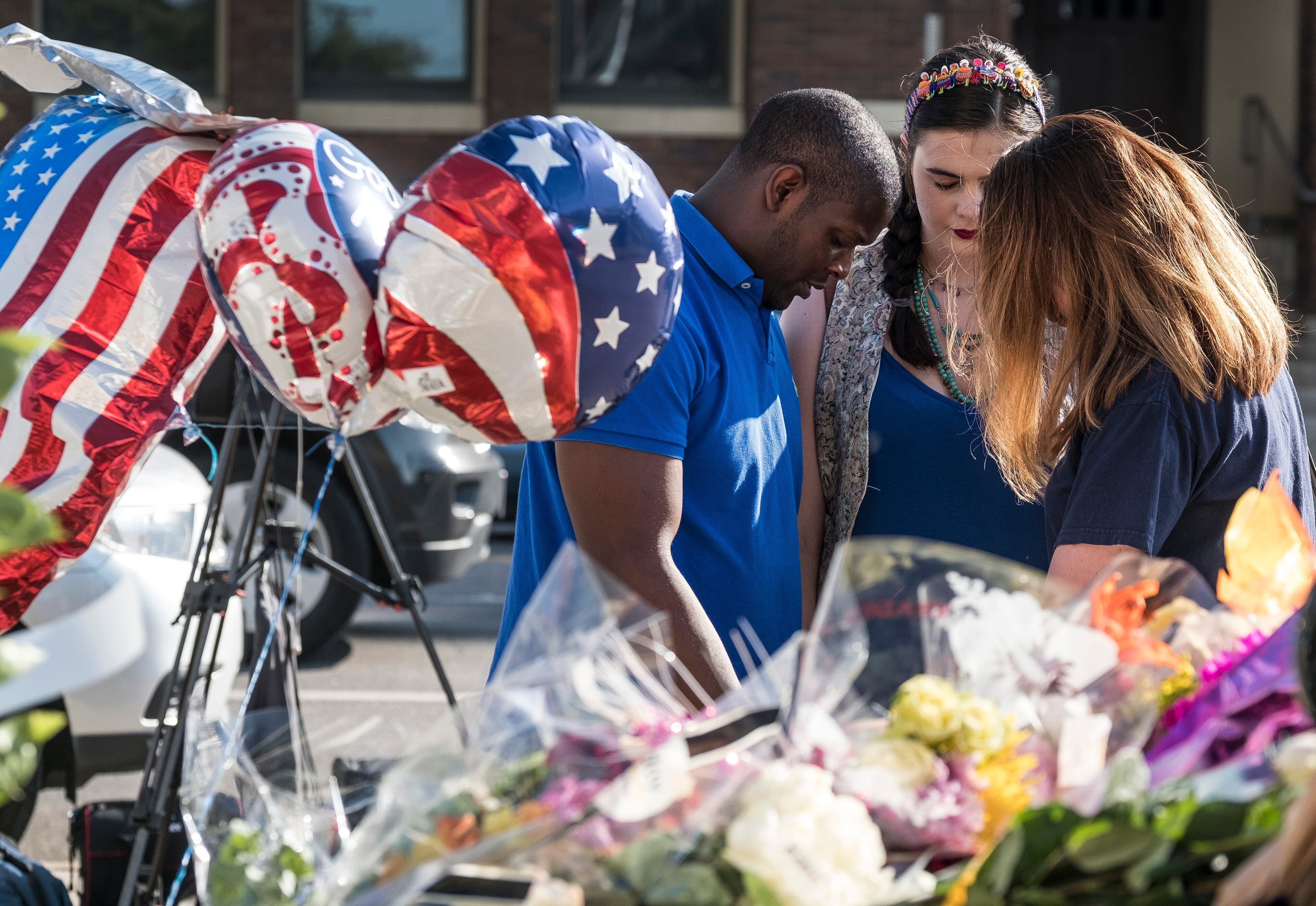 July 8, 2016 - Phillip Frazier, left, and Katherine Person, center, (women on right did not give name) pray together as they pay their respects at a memorial of flowers, gifts and cards placed on Dallas patrol cars in front of the Dallas Police department headquarters in Dallas, Texas, on Friday, July 8, 2016. Five officers were killed, six officers wounded along with two civilians were shot by suspected sniper Micah Johnson. RODOLFO GONZALEZ / AUSTIN AMERICAN-STATESMAN