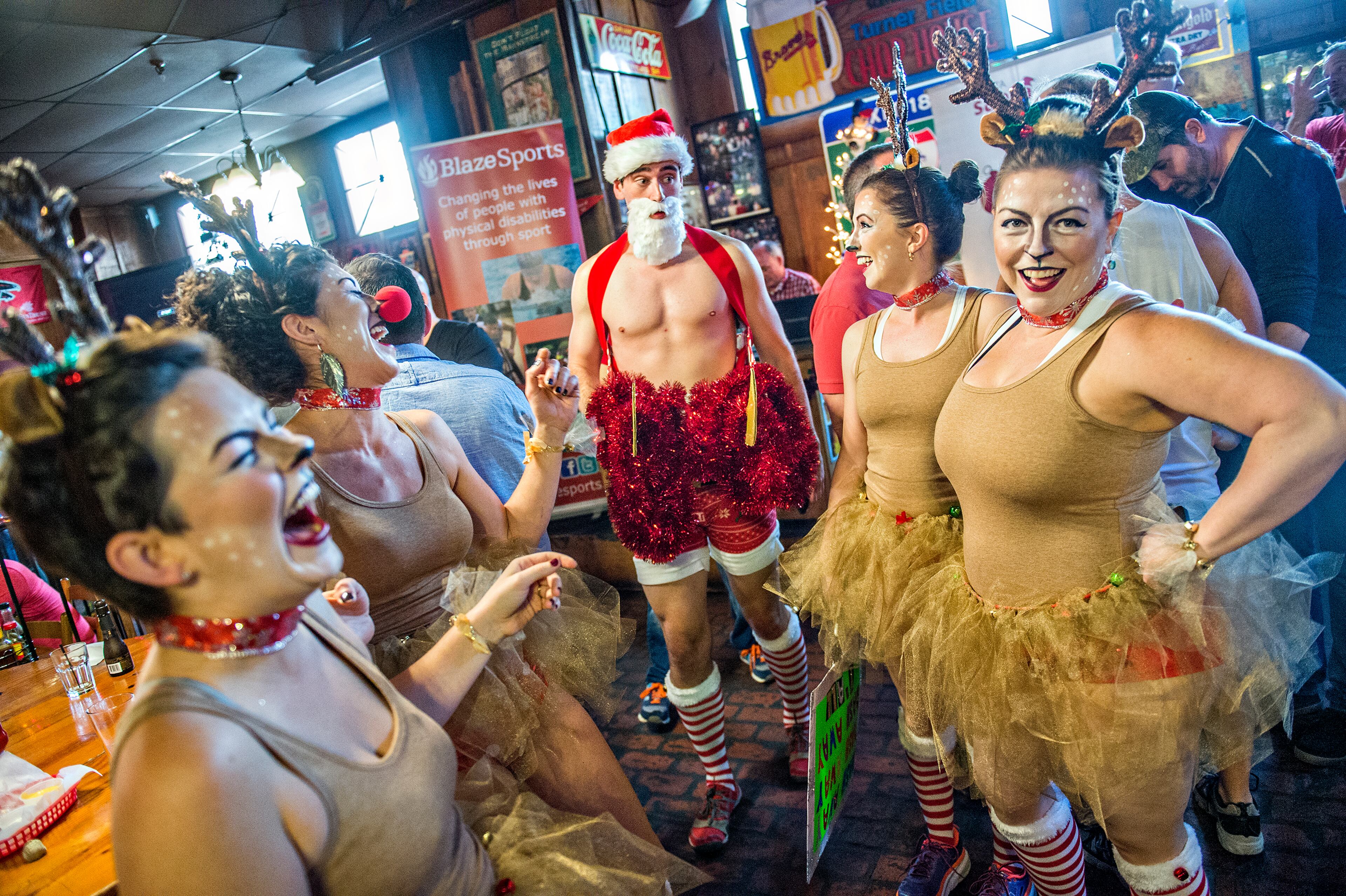 December 12, 2015 Atlanta - Dressed as Santa, Robert Cliatt (center) is introduced by his reindeer Sarah Cloud (left), Jennifer Harvey, Sarah McLean and Kellie Reese before the start of the annual Atlanta Santa Speedo Run at Manuel's Tavern in Atlanta on Saturday, December 12, 2015. The seventh annual fun run raised over $42,000 for BlazeSports. JONATHAN PHILLIPS / SPECIAL