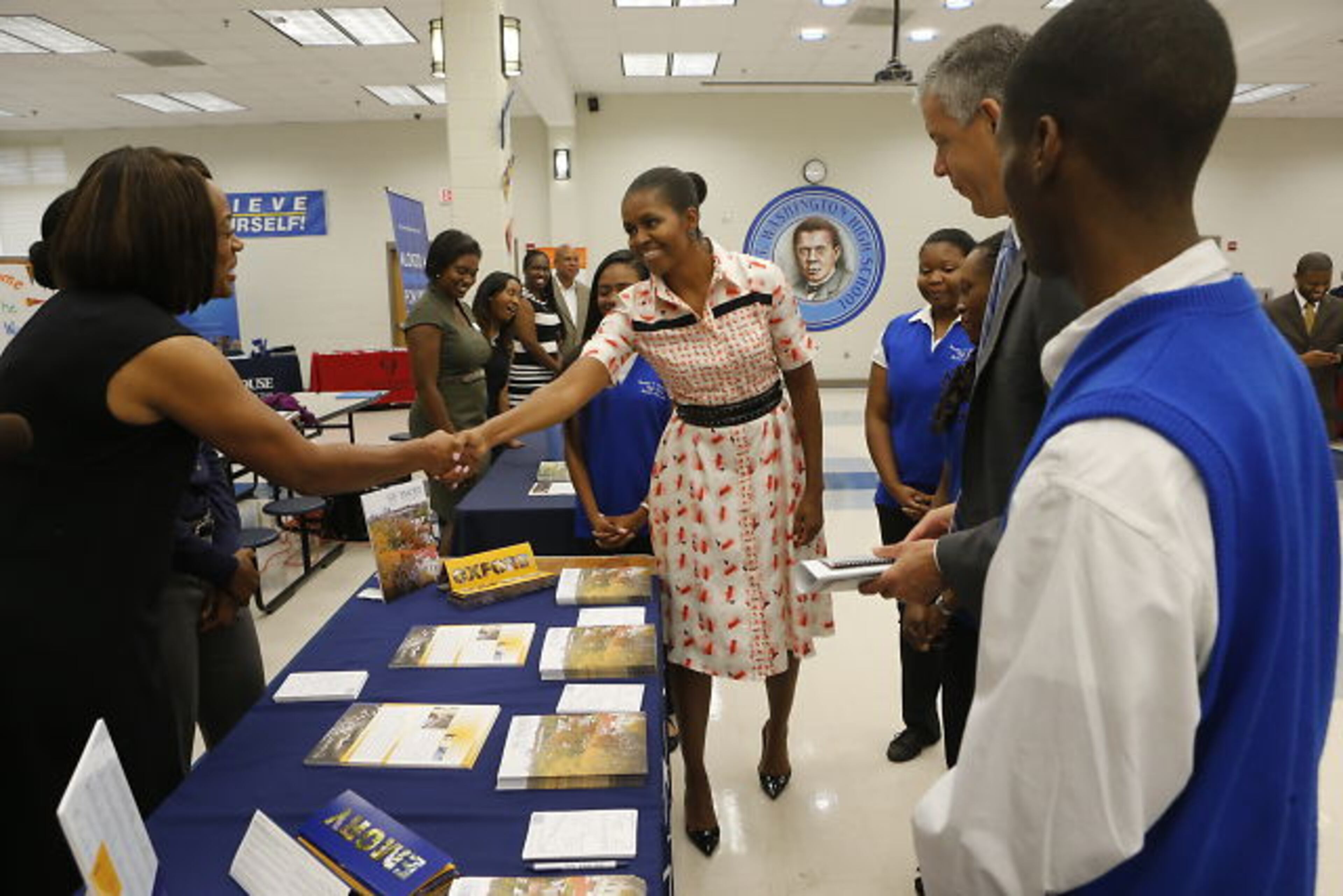 First Lady Michelle Obama arrives at Booker T. Washington to promote her "Reach Higher" initiative to increase the number of college graduates, greeting workers at the college fair as Secretary Duncan looks on.