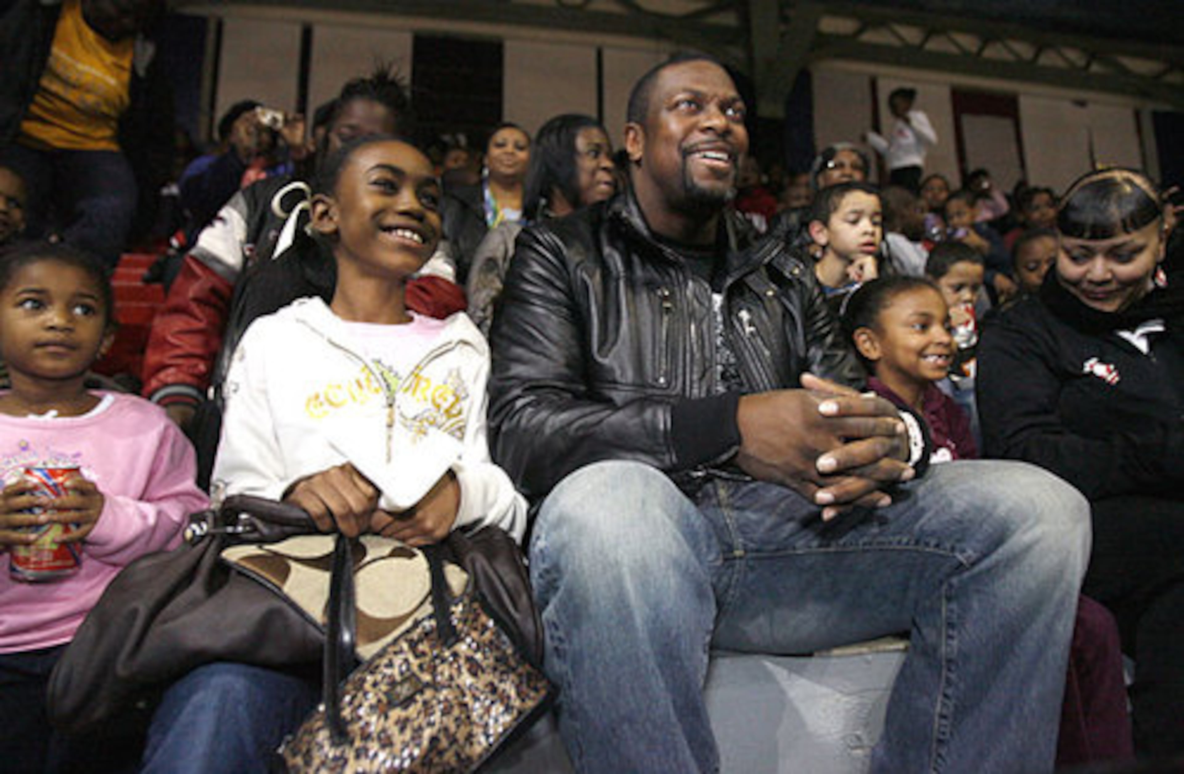 Chris Tucker sits with Zaire Gibbs, 10, and her sister Wynter Christian, 3, at left, while watching a performance during the holiday event.