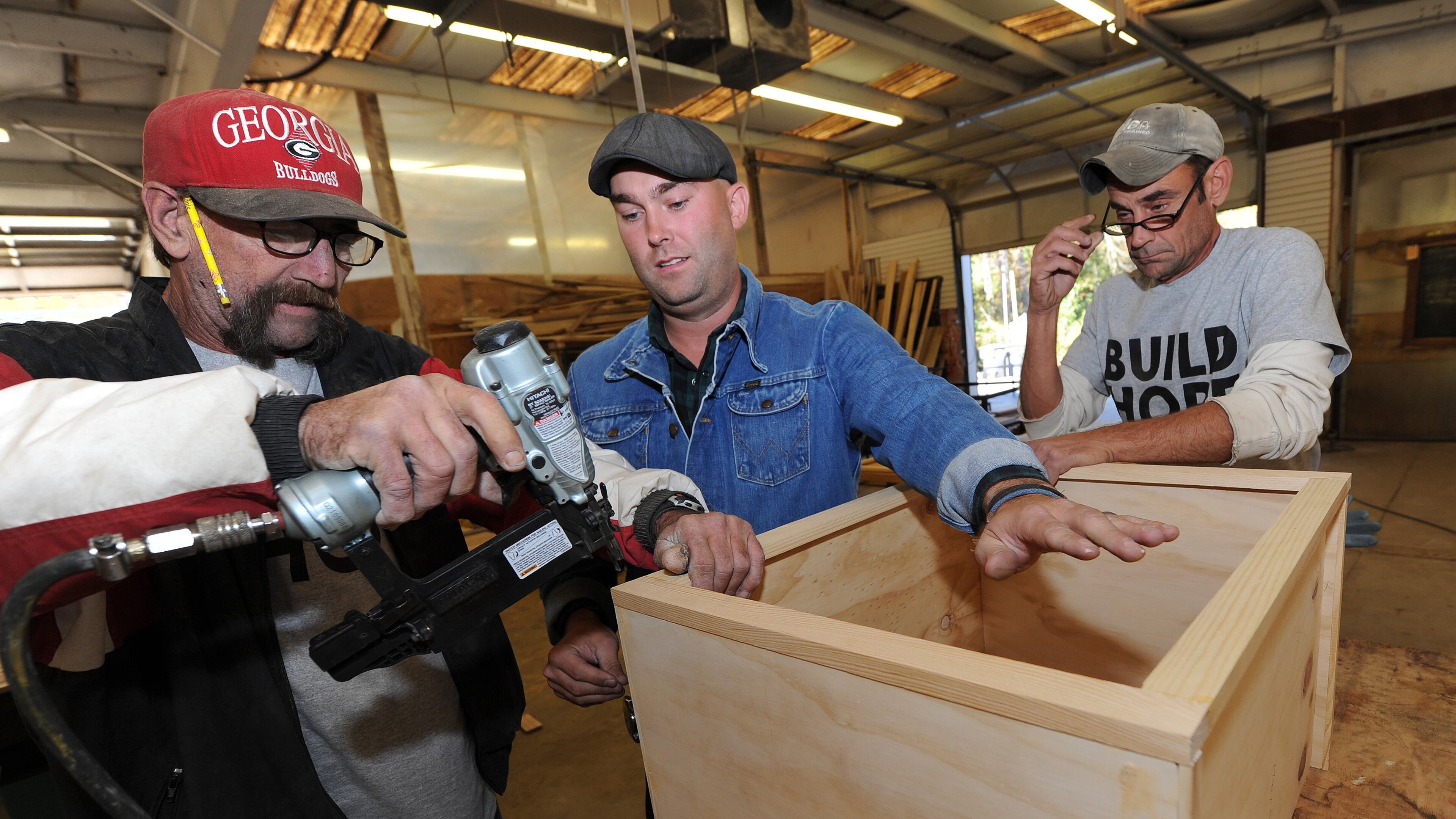 Brian Preston (center) with former workers Roger "TC" Curtis and Carl A Carlson as they assemble a piece of furniture. Staff file photo