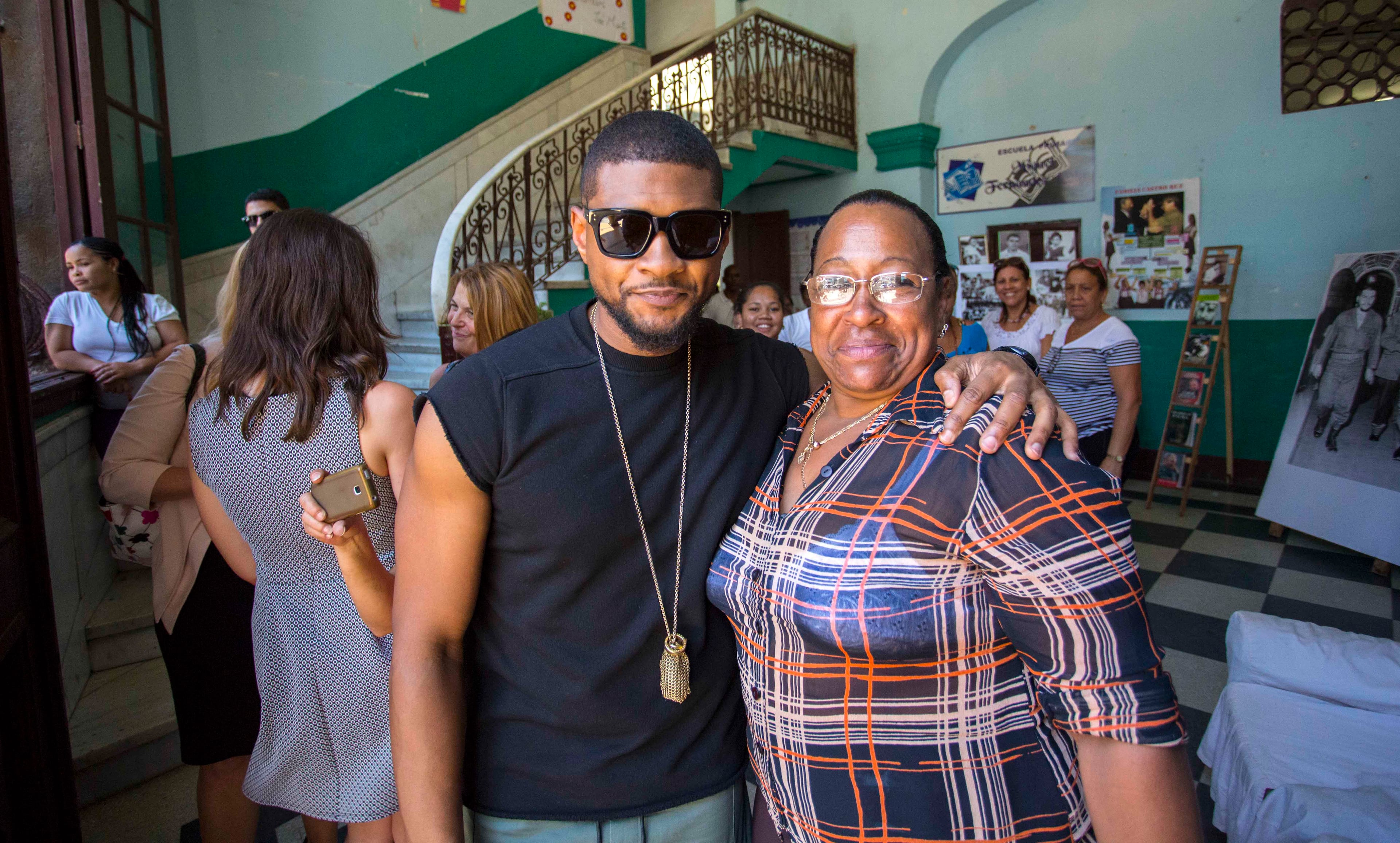 American artist Usher poses for a picture with school director Caridad Reyes at the Miguel Fernandez Roig primary school in Havana, Cuba, Tuesday, April 19, 2016. The U.S. President's Committee on Arts and the Humanities, including musicians Smokey Robinson, Usher and Dave Matthews, are on a four-day visit in Cuba. (AP Photo/Desmond Boylan)