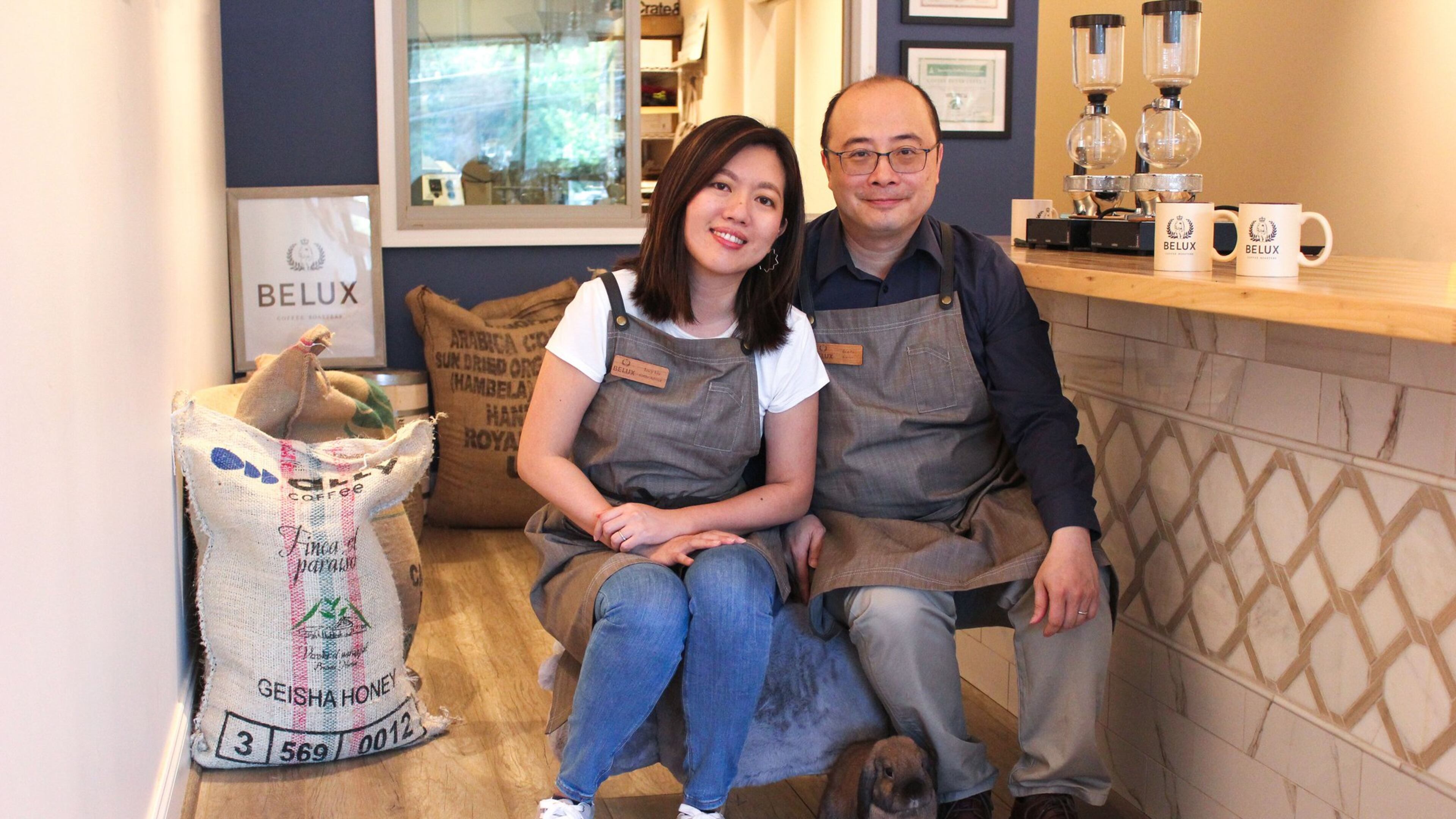 Bela, a Holland Lop rabbit, sits at the feet of Lucy Liu (left) and Ben Li of Belux Coffee Roasters. The pet bunny inspired the name of their company, and his image is on their logo. CONTRIBUTED BY DEBORA FANG