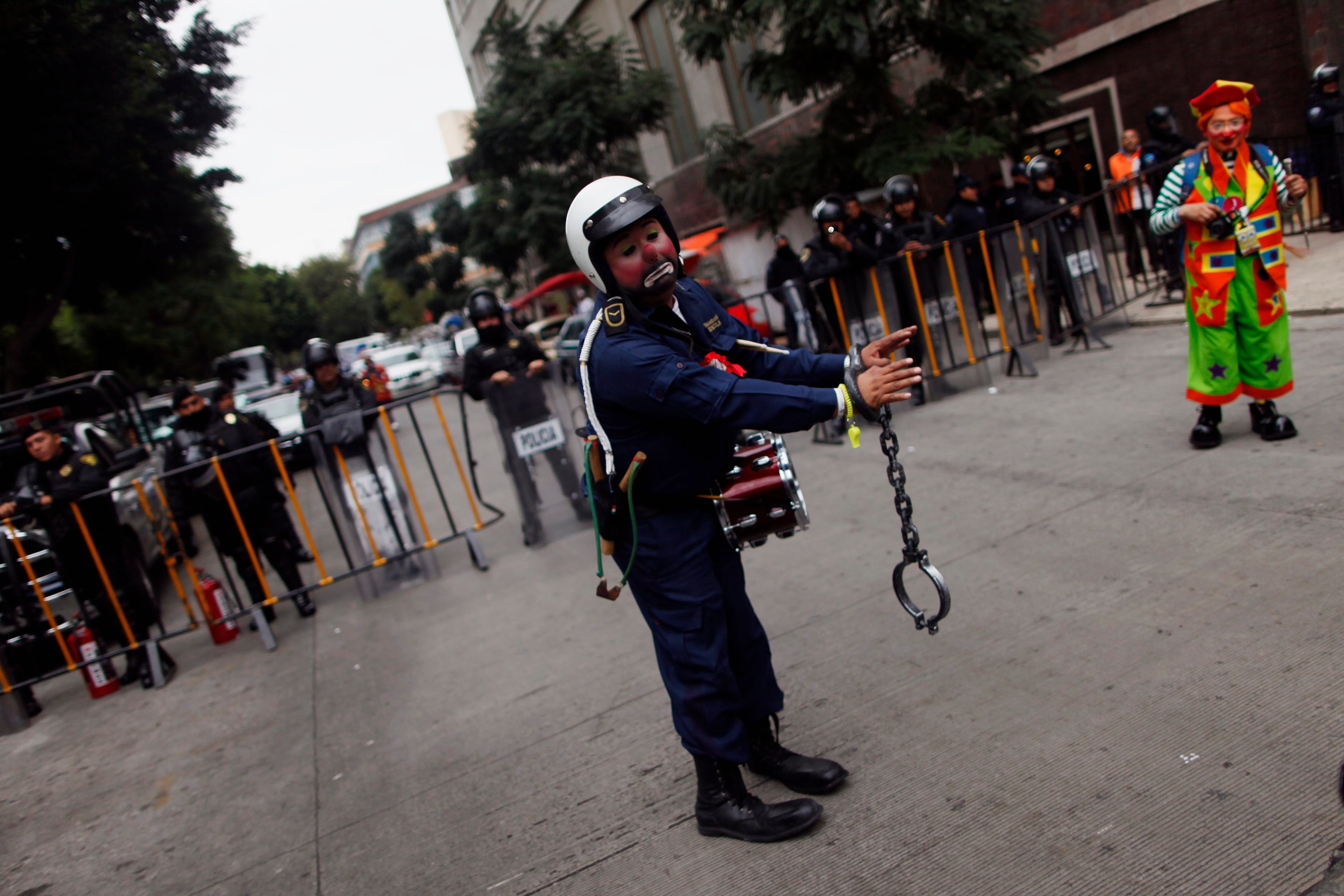 A clown dressed as a police officer performs in front of a line of police officers as he rallies for peace during the 18th Latin American clown convention or "Fair of laughter" at Reforma avenue in Mexico City October 23, 2013.