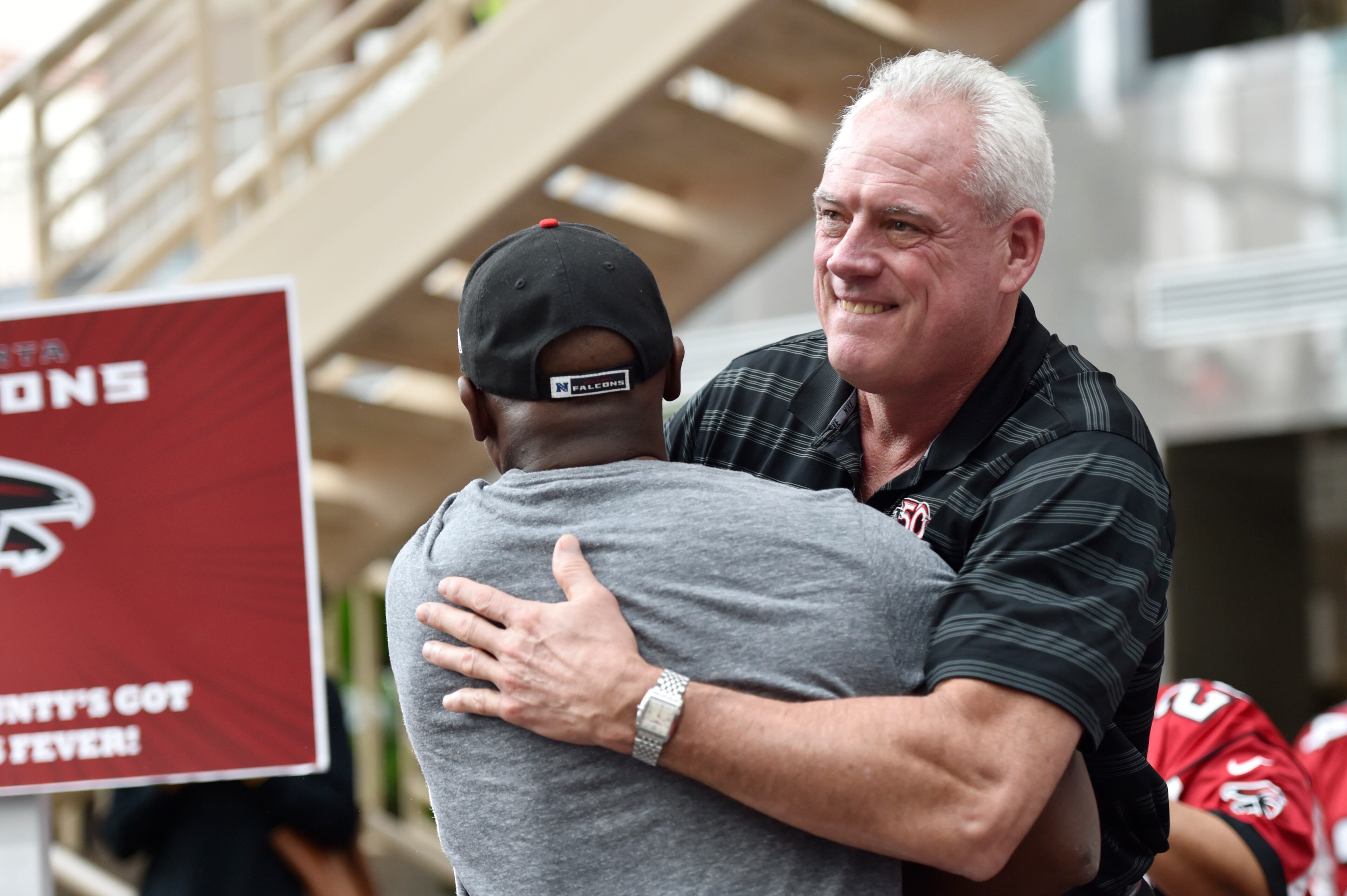January 20, 2017, Atlanta - Former Falcons wide receiver Terence Mathis, center, and former offensive tackle Mike Kenn, right, hug during a pep rally for the upcoming NFC Championship game against the Packers in Atlanta, Georgia, on Friday, January 20, 2017. (DAVID BARNES / DAVID.BARNES@AJC.COM)