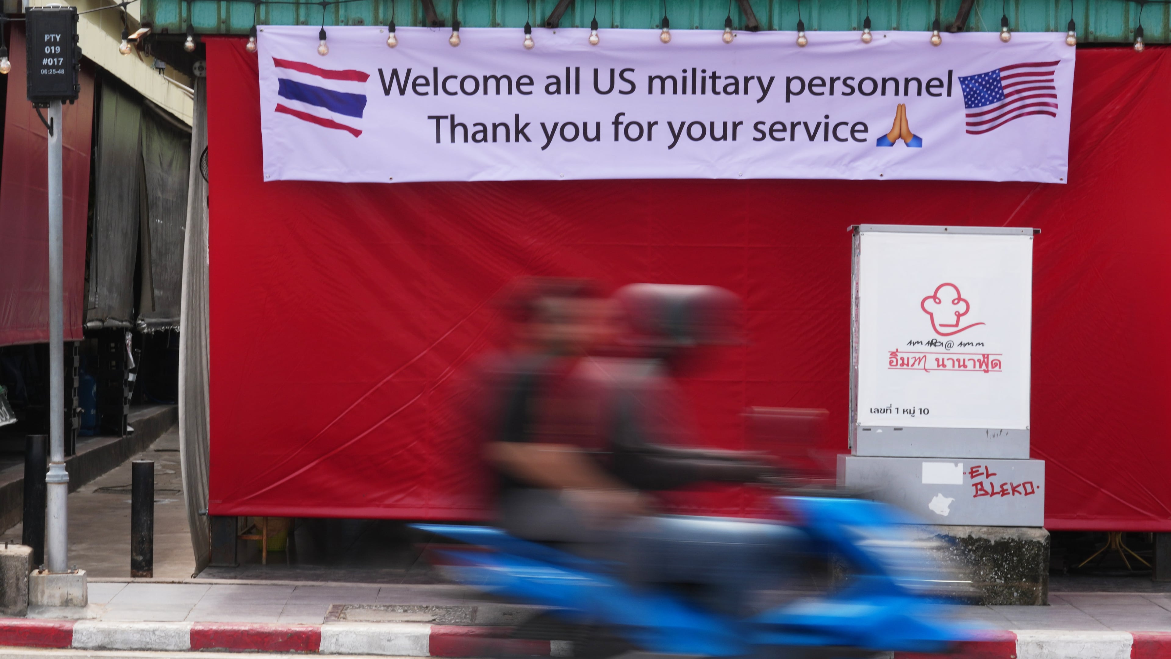A motorcycle taxi drives past a banner in Pattaya, Thailand, Tuesday, Sept. 1, 2026. (AP Photo/Sakchai Lalit)
