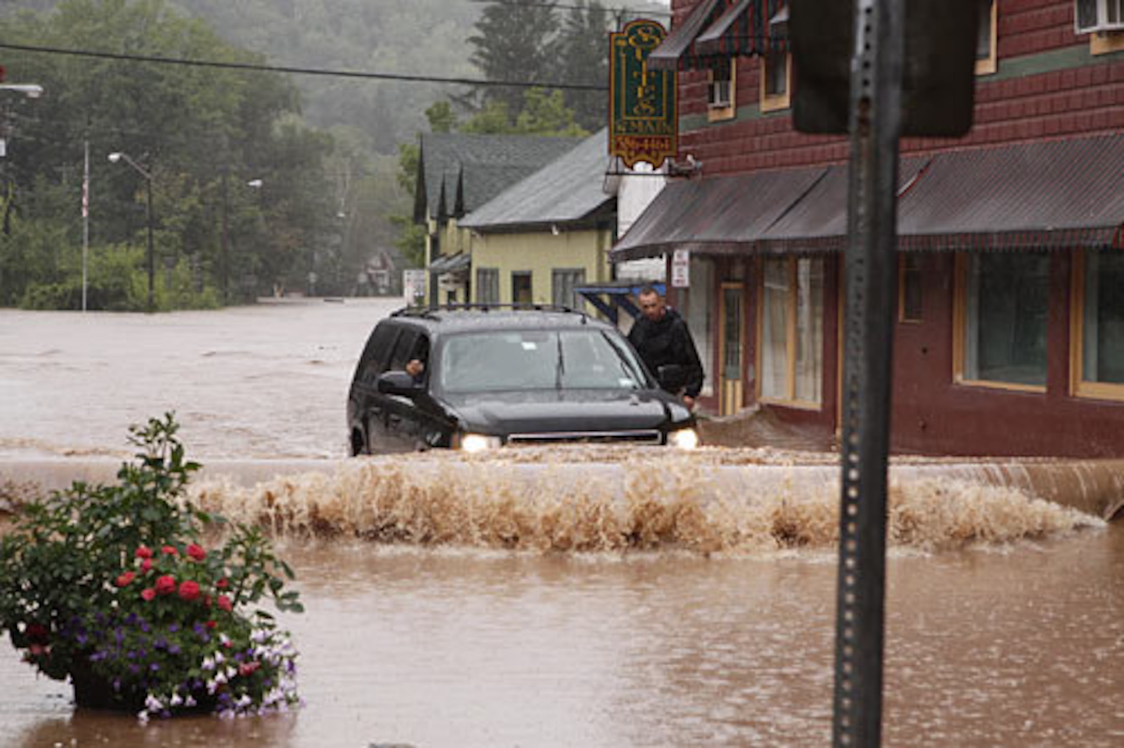 A security guard hangs on the door of Gov. Andrew Cuomo's SUV in the middle of a flooded street Sunday, Aug. 28, 2011, in Margaretville, N.Y. Gov. Cuomo was riding in the SUV, and posted some photos of the heavy flooding on his flickr site. Torrential rains from Tropical Storm Irene forced hundreds in the Hudson Valley from their homes, caused widespread power outages, closed 137 miles of the state's main highway and swelled creeks and rivers to previously unseen levels.