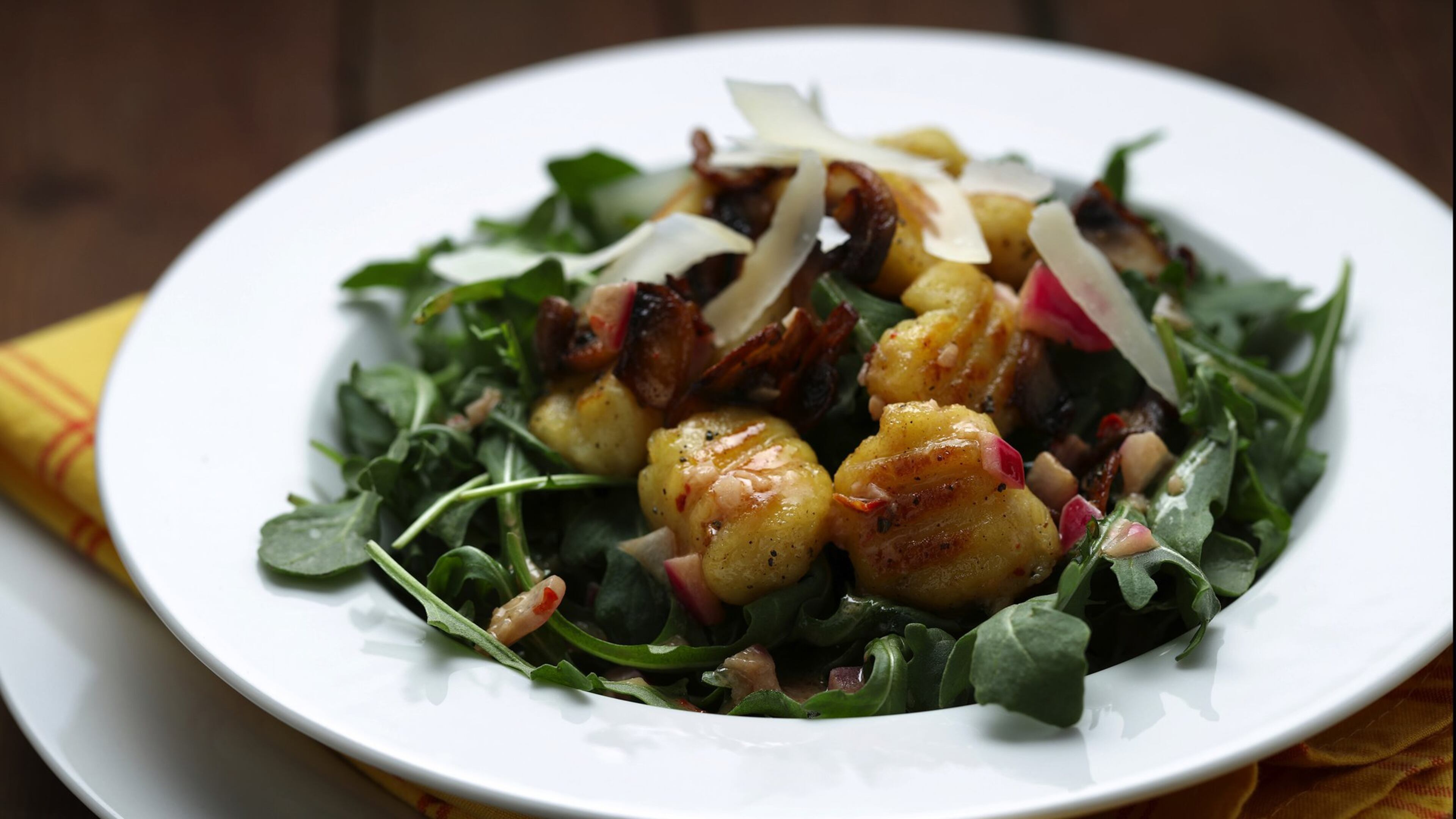 Potato gnocchi are browned in a skillet after boiling, then tossed with a simple vinaigrette and garnished with arugula, sauteed mushrooms and shaved Parmesan. (Mark Graham/food styling) (E. Jason Wambsgans/Chicago Tribune/TNS)