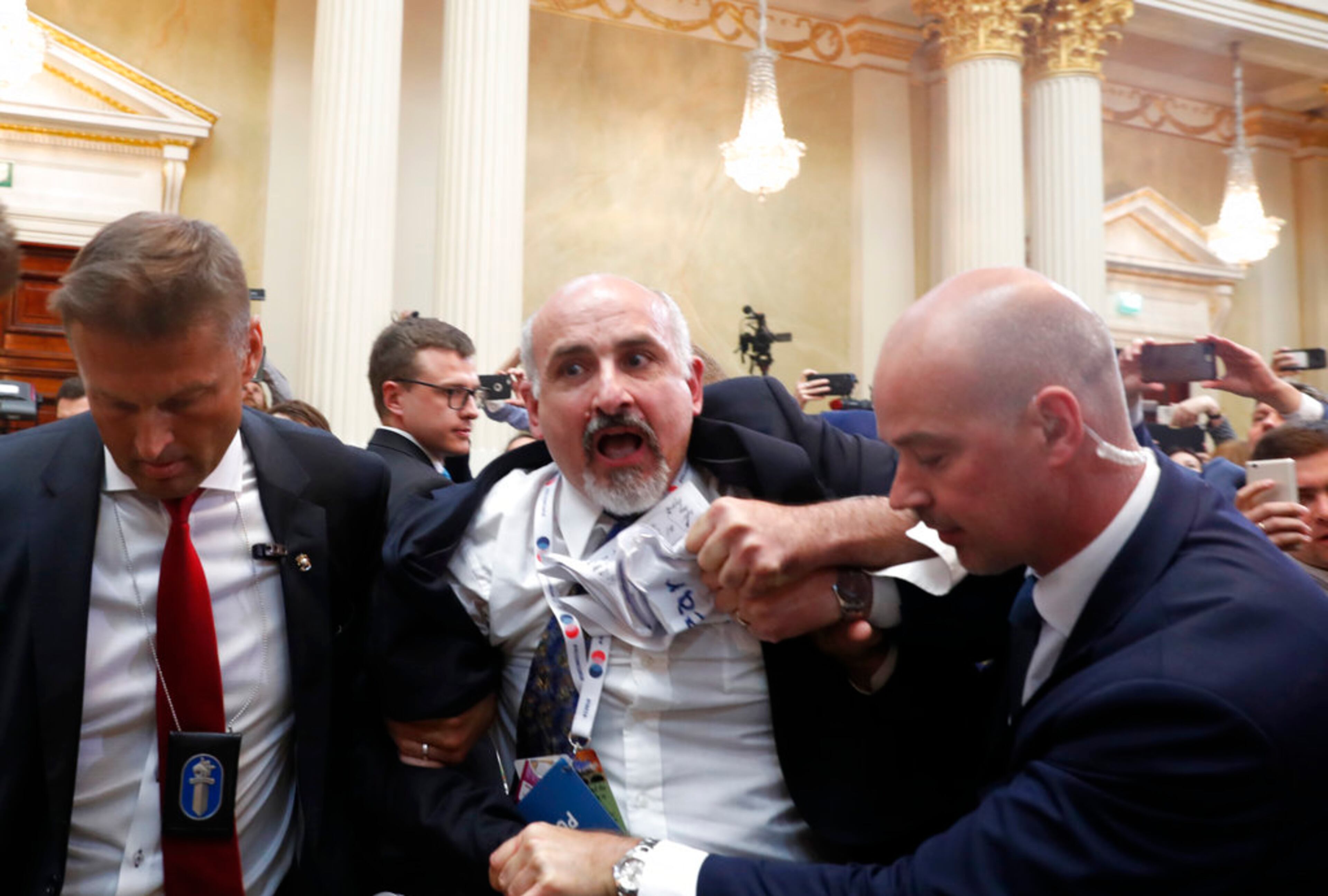 A man is shoved out of the room after showing prior to a press conference after the meeting of U.S. President Donald Trump and Russian President Vladimir Putin at the Presidential Palace in Helsinki, Finland, Monday, July 16, 2018. (AP Photo/Pablo Martinez Monsivais)