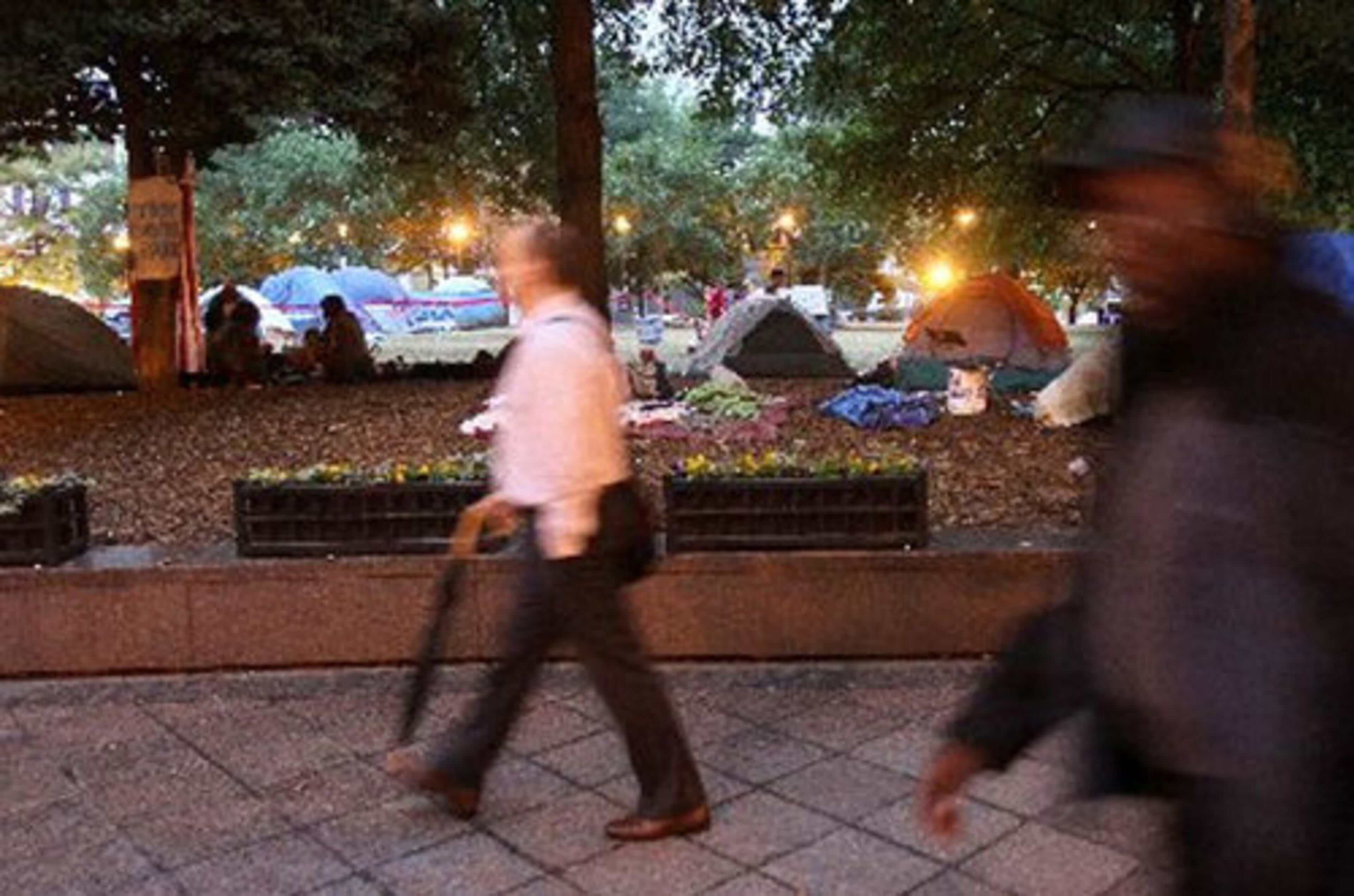 Pedestrians walk by campers before sunrise as Occupy Atlanta continues to rally against corporate greed and on behalf of an assortment of progressive causes.
