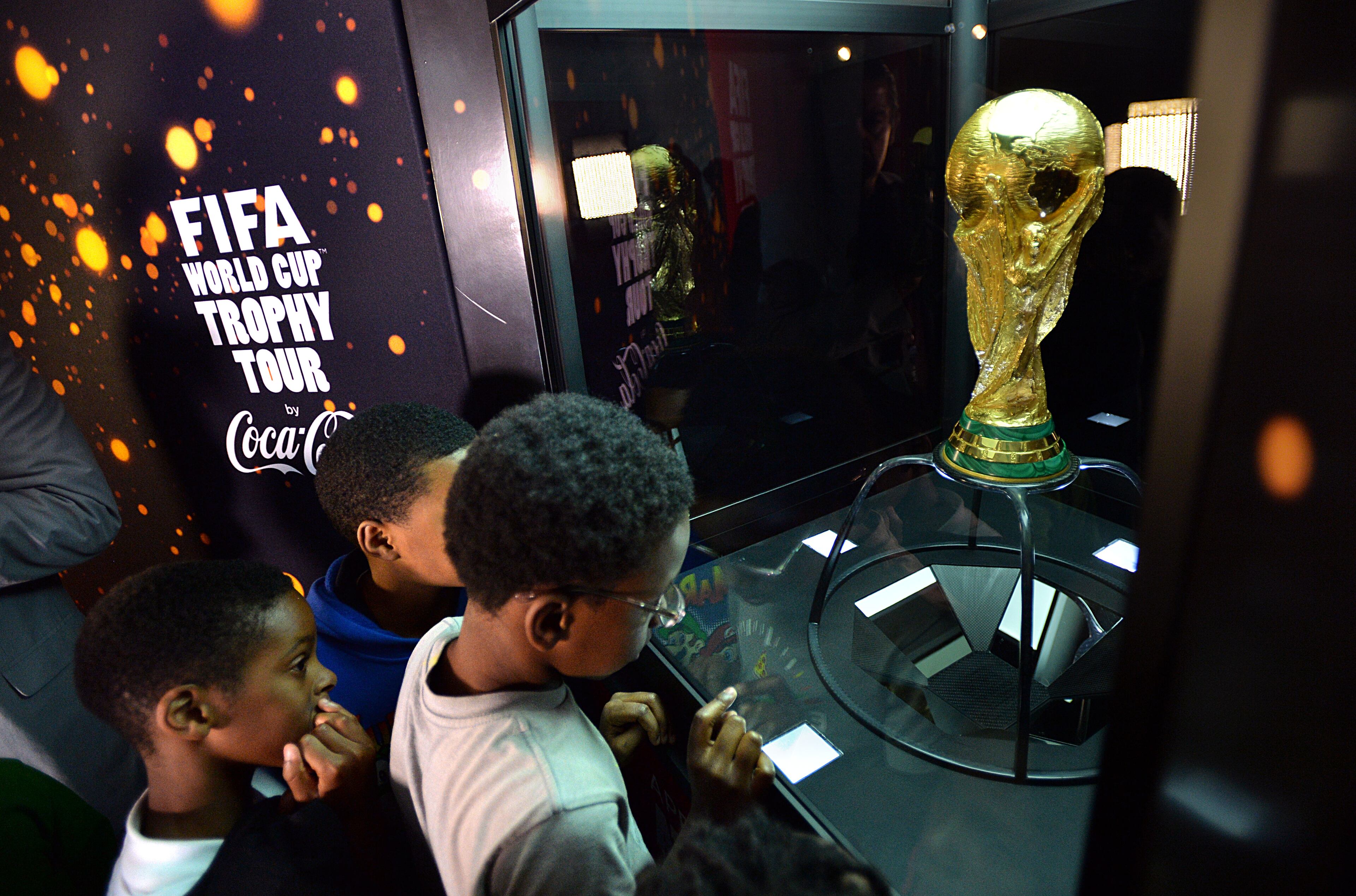 Jaden Blake (right) and other children from Centers of Hope take a close look at the FIFA World Cup Trophy on display at Coca-Cola headquarters. HYOSUB SHIN / HSHIN@AJC.COM