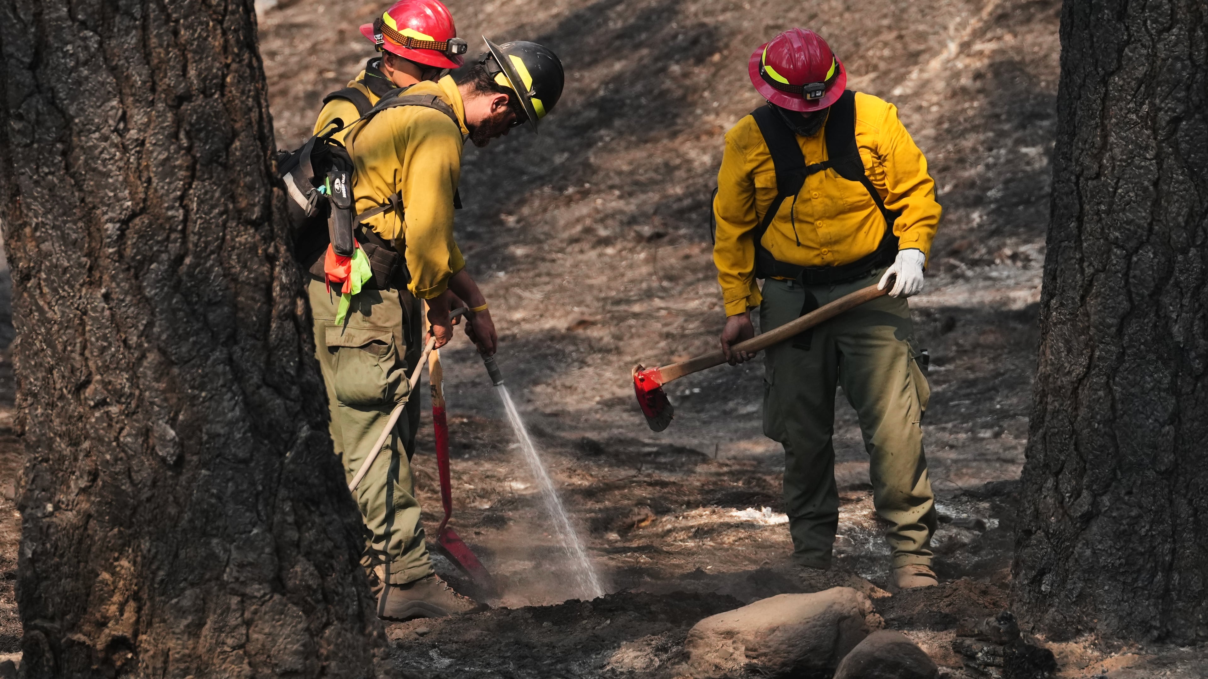 A crew does mop-up work in a burned area of Wyakin Park after a wildfire hit the northern part of Spokane, Wash., Tuesday, Aug. 4, 2026. (AP Photo/Lindsey Wasson)