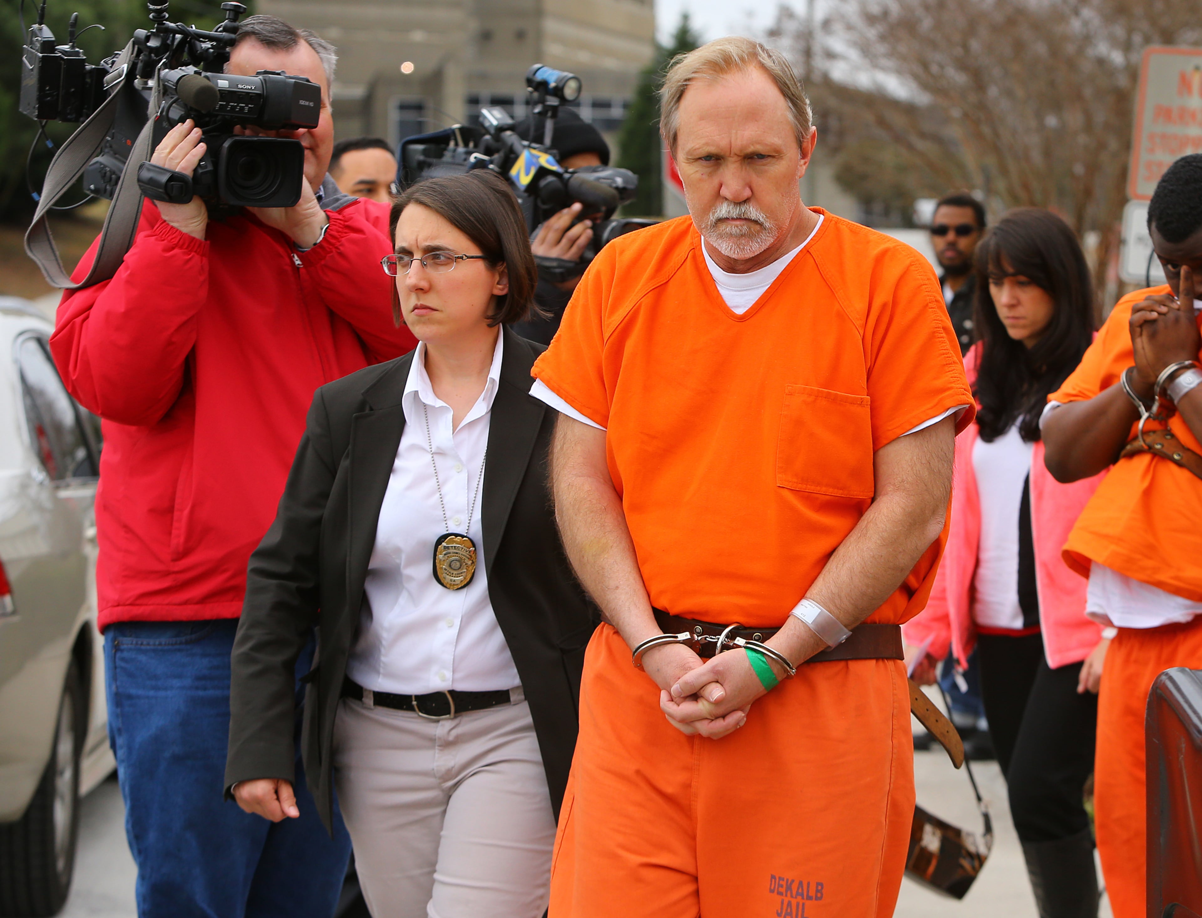 John McGill, principal of Mt. Carmel Elementary School in Douglas County, is led away in handcuffs following his first appearance hearing at DeKalb County Magistrate Court for a felony offense of electronic pornography and attempting to have sex with a minor on Tuesday, March 4, 2014, in Decatur.