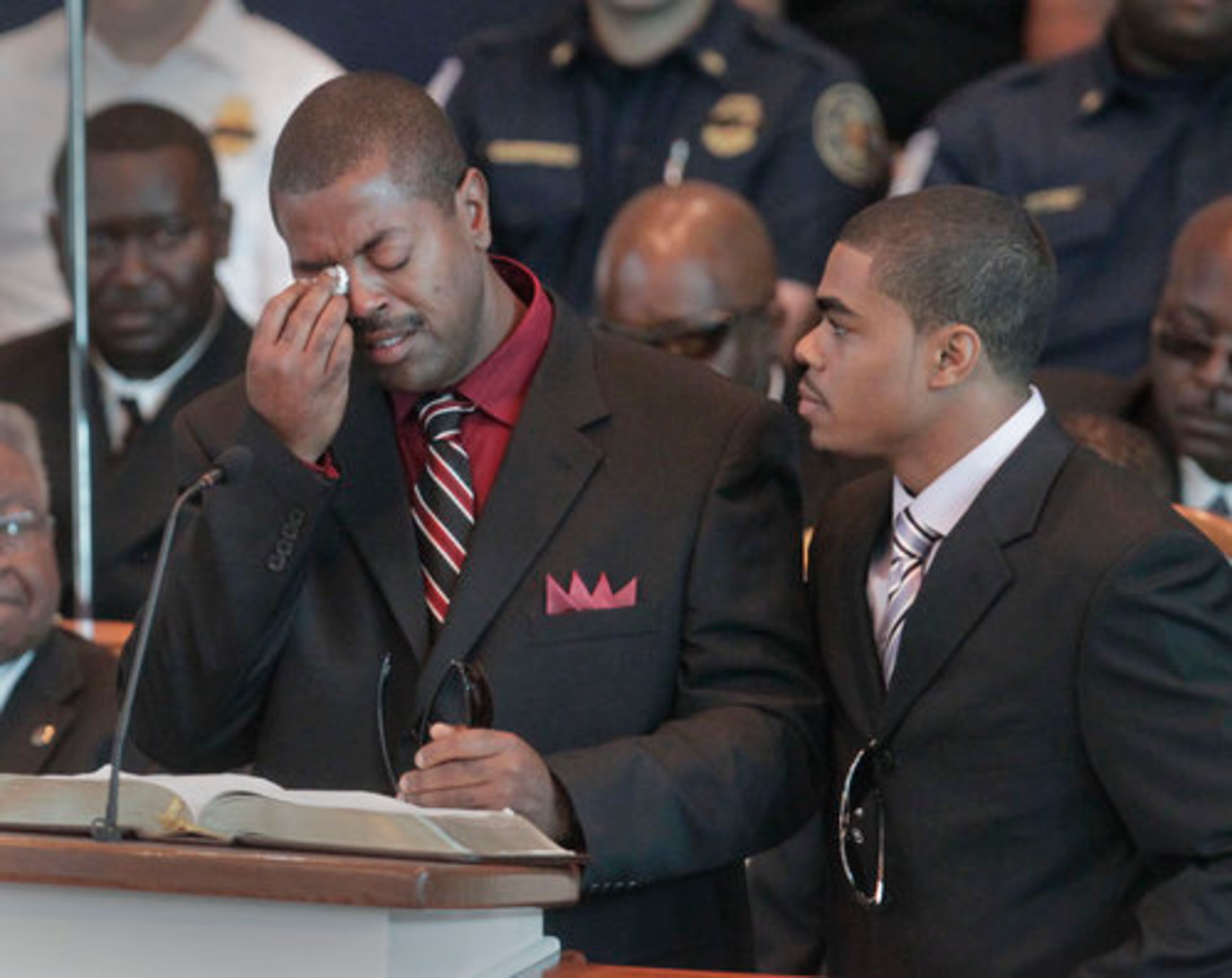 Hoover Sirmans, friend and golfing buddy, is comforted by Carl Blake's son, Travis, while making remarks during the service.