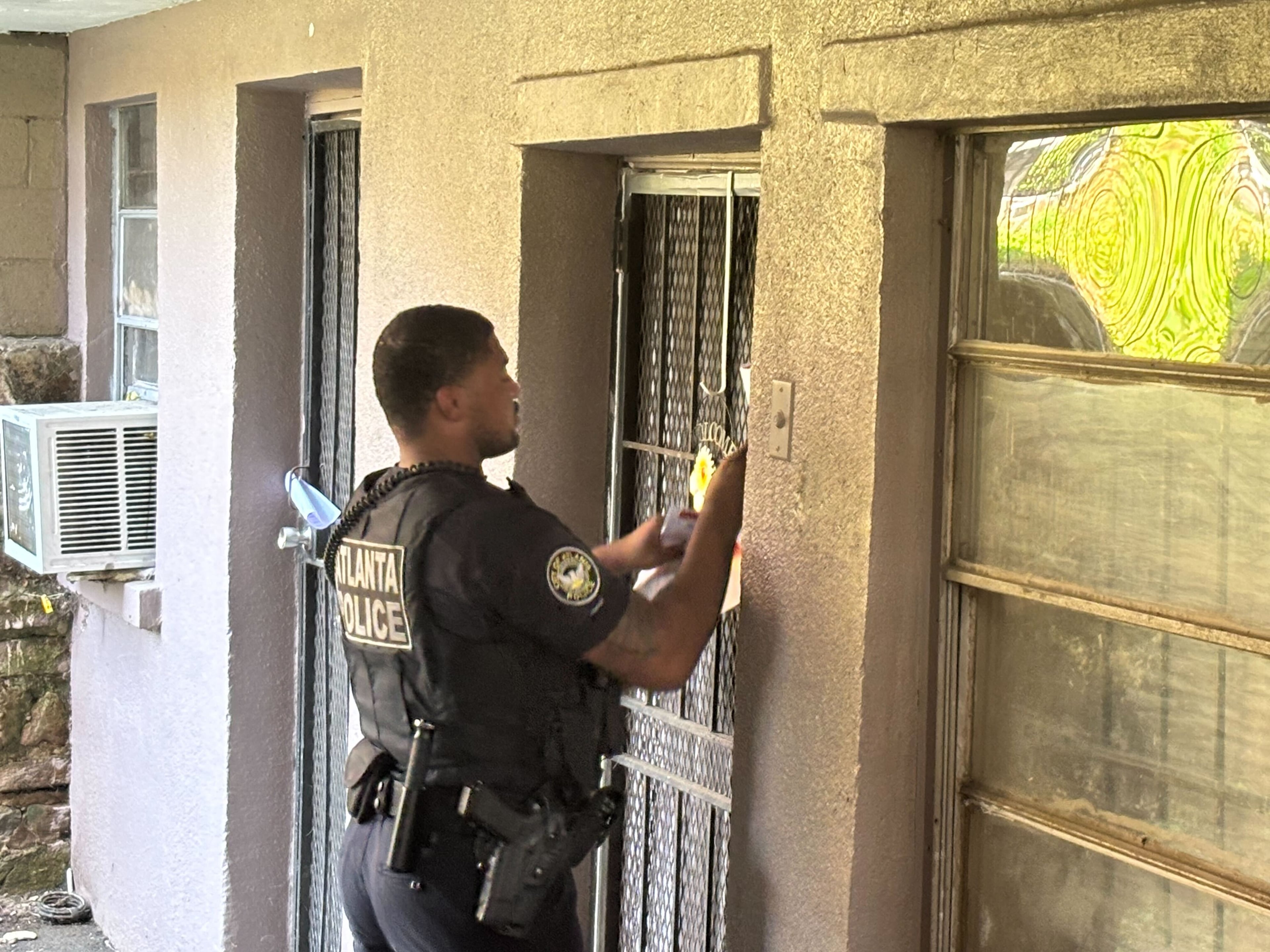 An officer is seen placing a flyer on a resident's door Wednesday afternoon on Verbena Street in northwest Atlanta. (David Aaro/AJC)