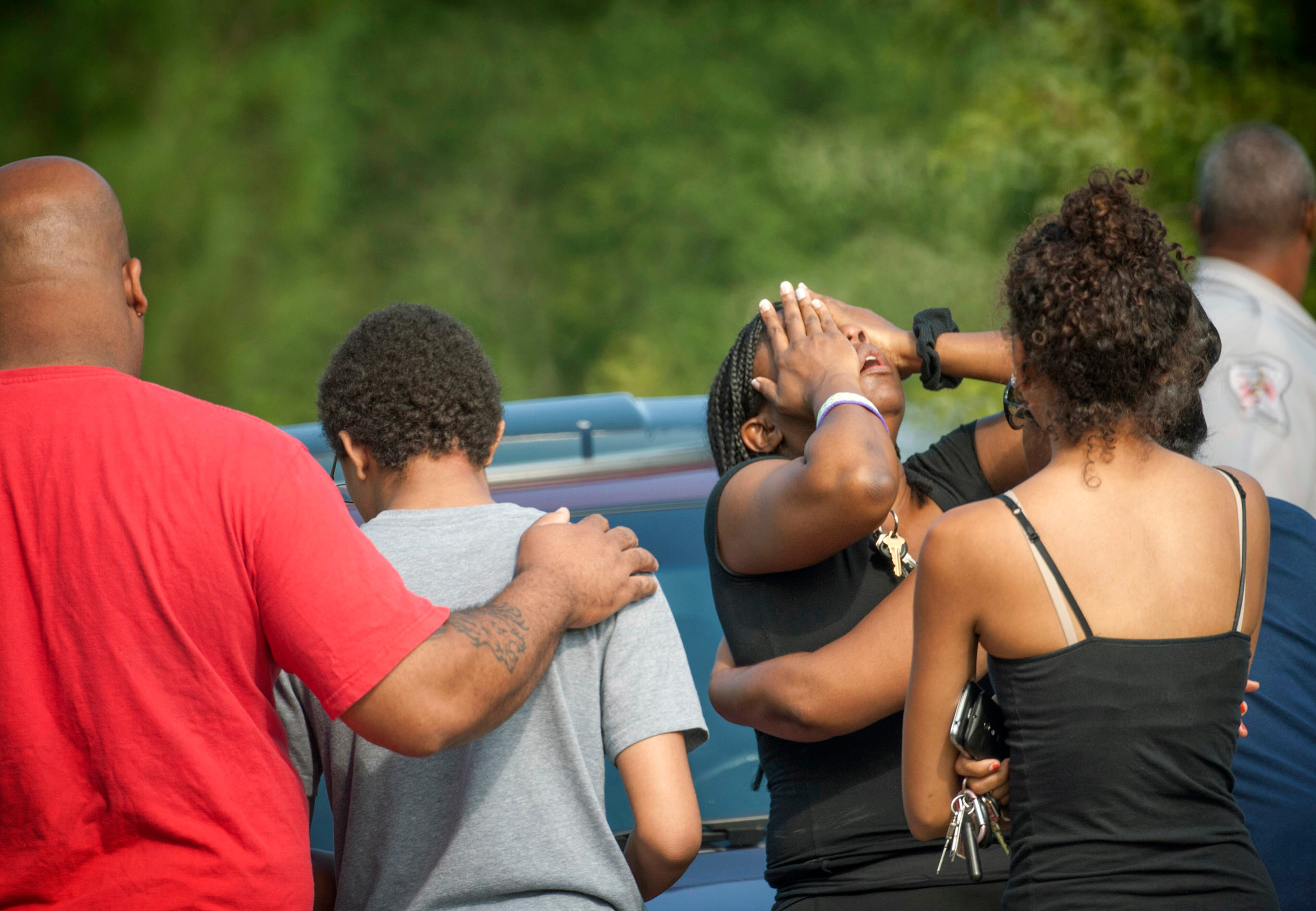 People comfort each other after a shooting in Fayetteville, N.C., Wednesday, July 30, 2014. A domestic dispute erupted into a gun battle with deputies Wednesday at a North Carolina mobile home park, leaving three people dead and three officers wounded, officials said.