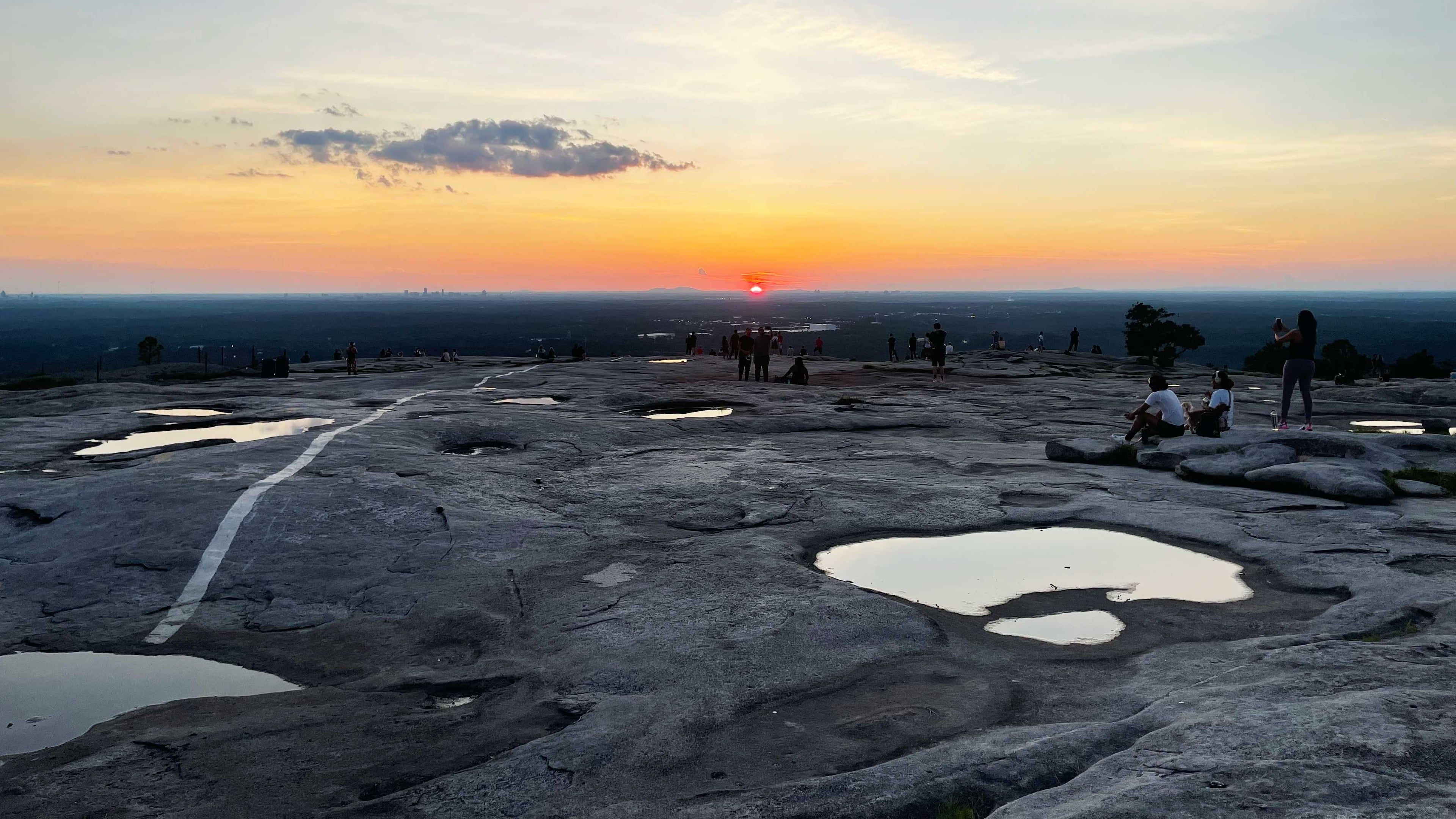 Near the end of the longest day of the year, Georgians rest atop Stone Mountain to watch the sunset behind the Atlanta skyline. (Richard Watkins/AJC)
