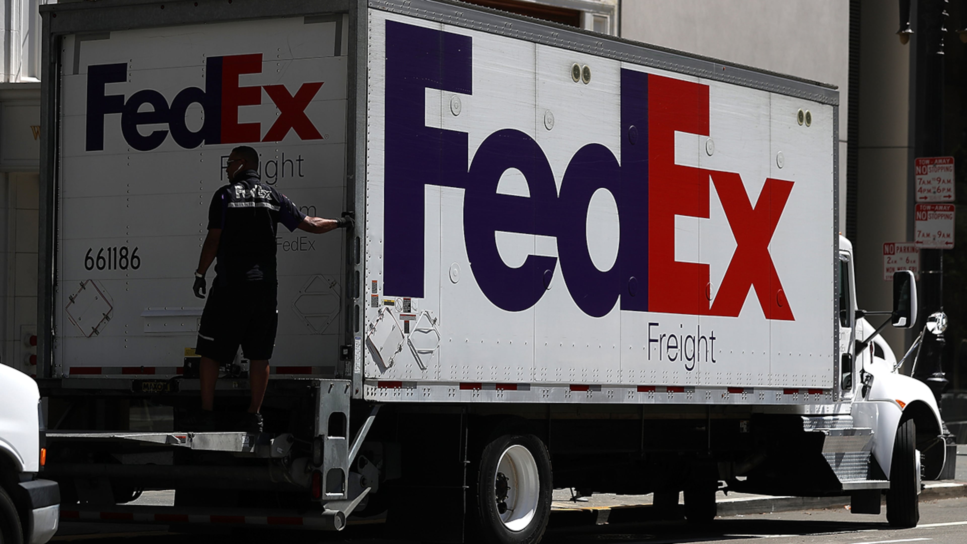 A FedEx worker closes the roll up door of a delivery truck. FedEx, U.S. Postal Service and UPS each have ways customers can report and avoid email scams.