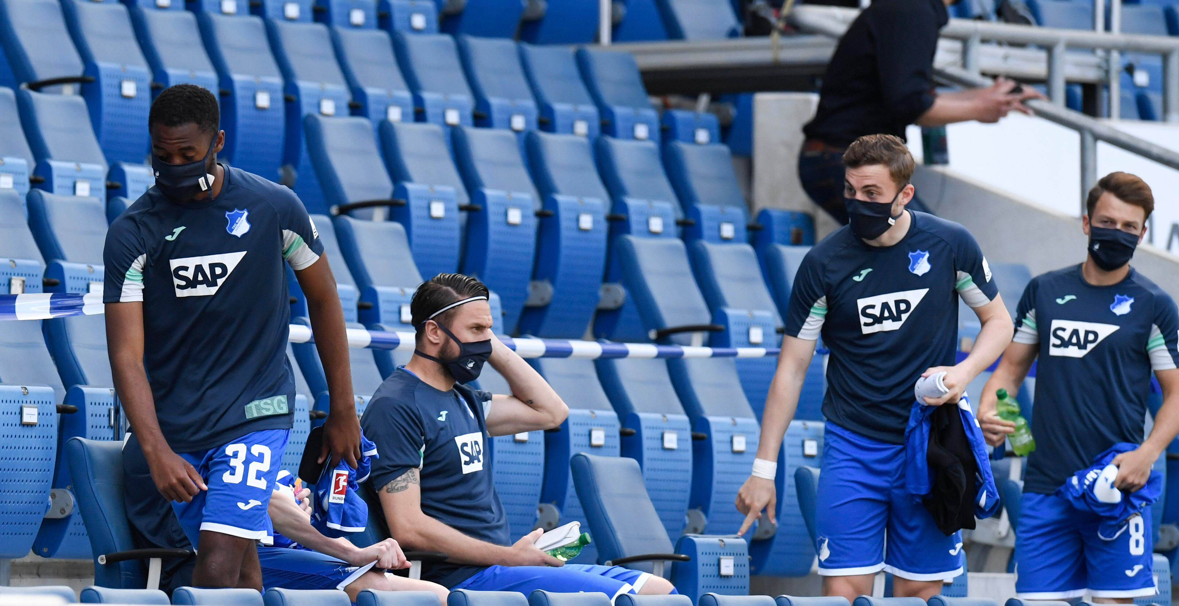 Hoffenheim's Melayro Bogarde, left, and teammates take their seats in the stands instead on the substitution bench to keep distance during the Bundesliga soccer match between TSG 1899 Hoffenheim and Hertha BSC Berlin in Sinsheim, Germany, Saturday, May 16, 2020. The German Bundesliga becomes the world's first major soccer league to resume after a two-month suspension because of the coronavirus pandemic. (Thomas Kienzle/AFP pool via AP)