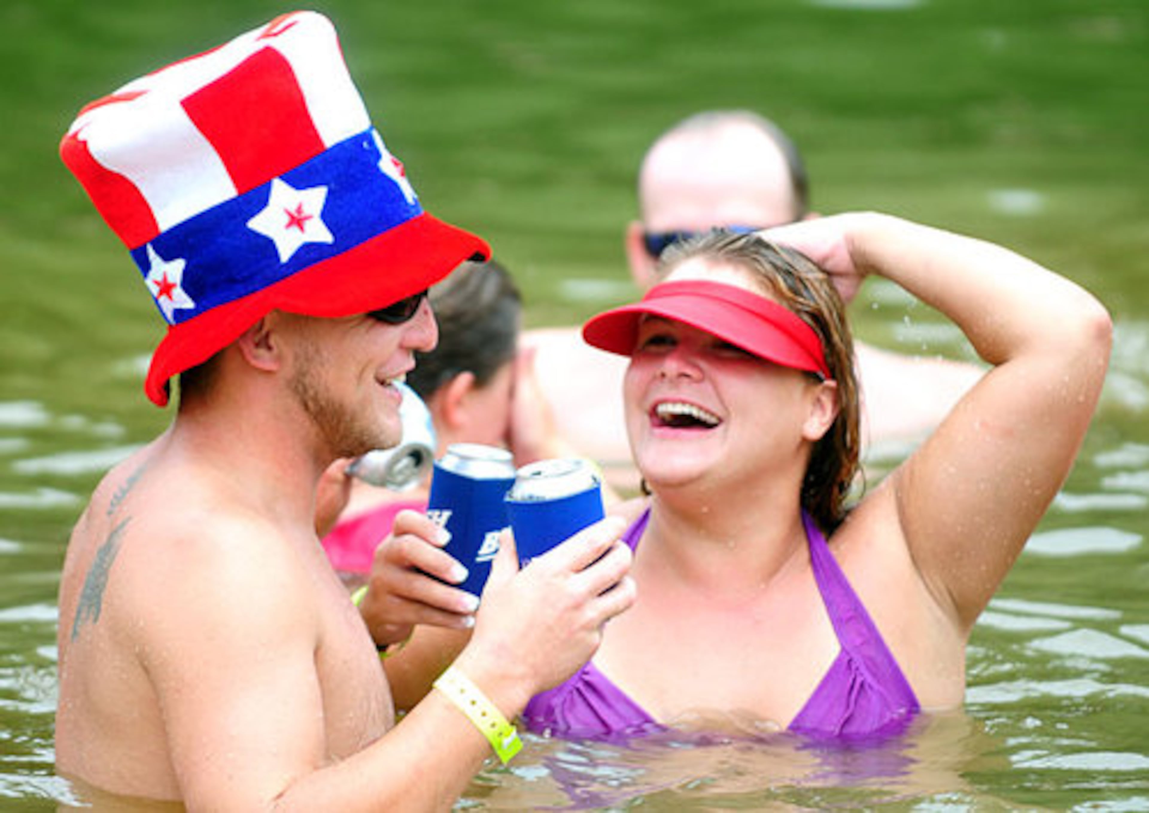 Brian Simpson, of Augusta, holds on to his Natty Light while cooling off in the Oconee River with his wife Marie.