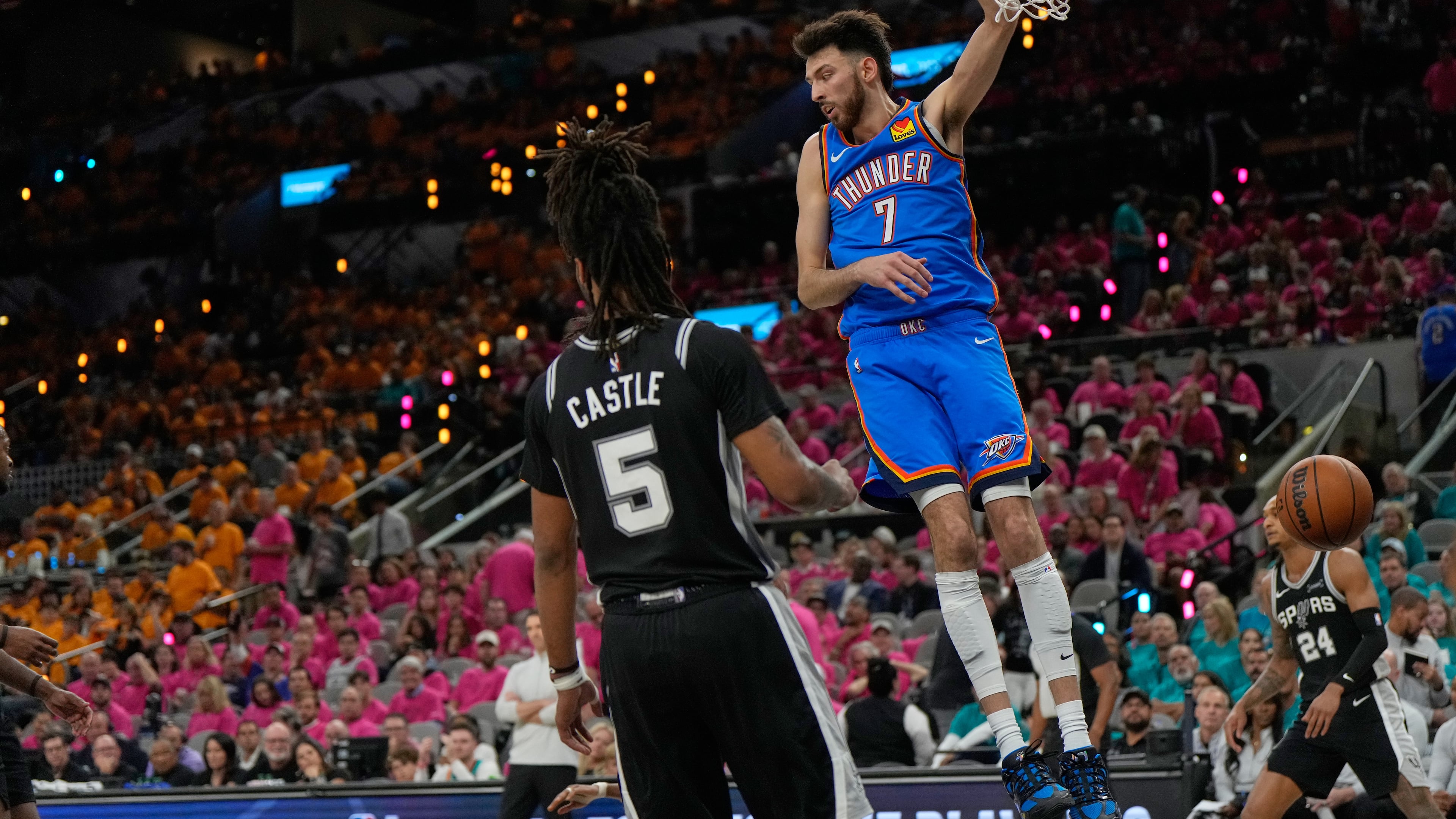Oklahoma City Thunder center Chet Holmgren (7) hangs on the rim next to San Antonio Spurs guard Stephon Castle (5) after a dunk during the second half of Game 3 in the Western Conference finals NBA basketball playoffs series Friday, May 22, 2026, in San Antonio. (AP Photo/Ashley Landis)