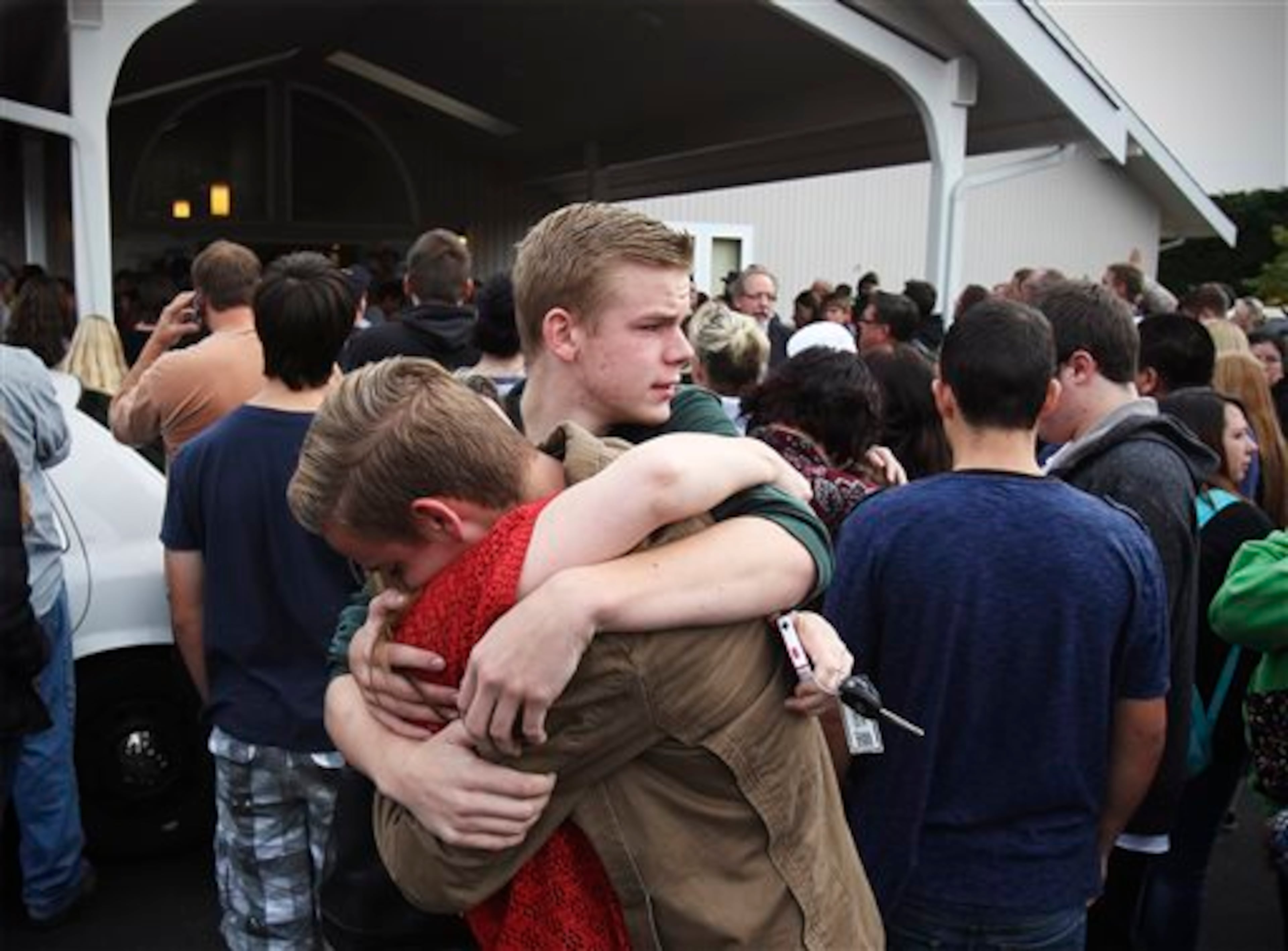 Brothers Wyatt and Noah Langstraat hug their mother Michelle Langstraat after being reunited at the Shoultes Christian Assembly, Friday, Oct. 24, 2014. Noah Langstraat, 15, was in the cafeteria at Marysville-Pilchuck High School Friday morning during the school shooting. A student walked into his Seattle-area high school cafeteria on Friday and without shouting or arguing, opened fire, killing one person and shooting several others in the head before turning the gun on himself, officials and witnesses said. (AP Photo/The Herald, Genna Martin)