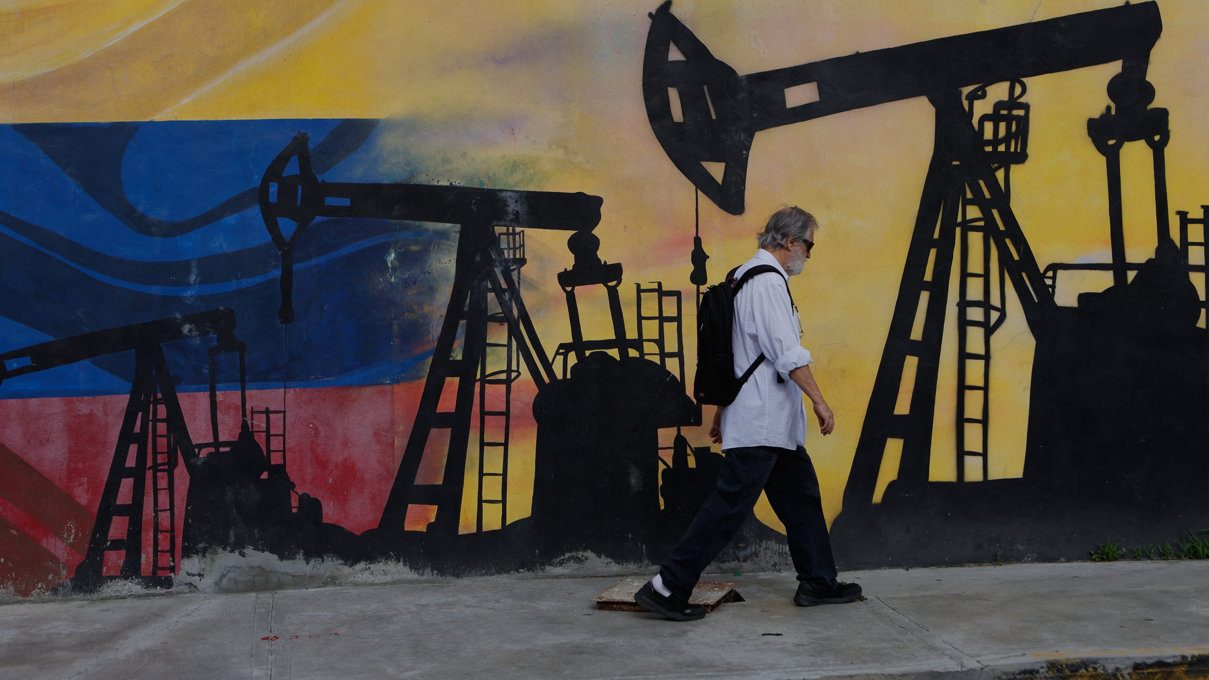 A pedestrian walks past a mural featuring oil wells in Caracas, Venezuela, Saturday, Aug 29, 2026, a day after President Donald Trump announced a deal giving the United States a stake in Venezuela’s oil reserves. (AP Photo/Pedro Mattey)