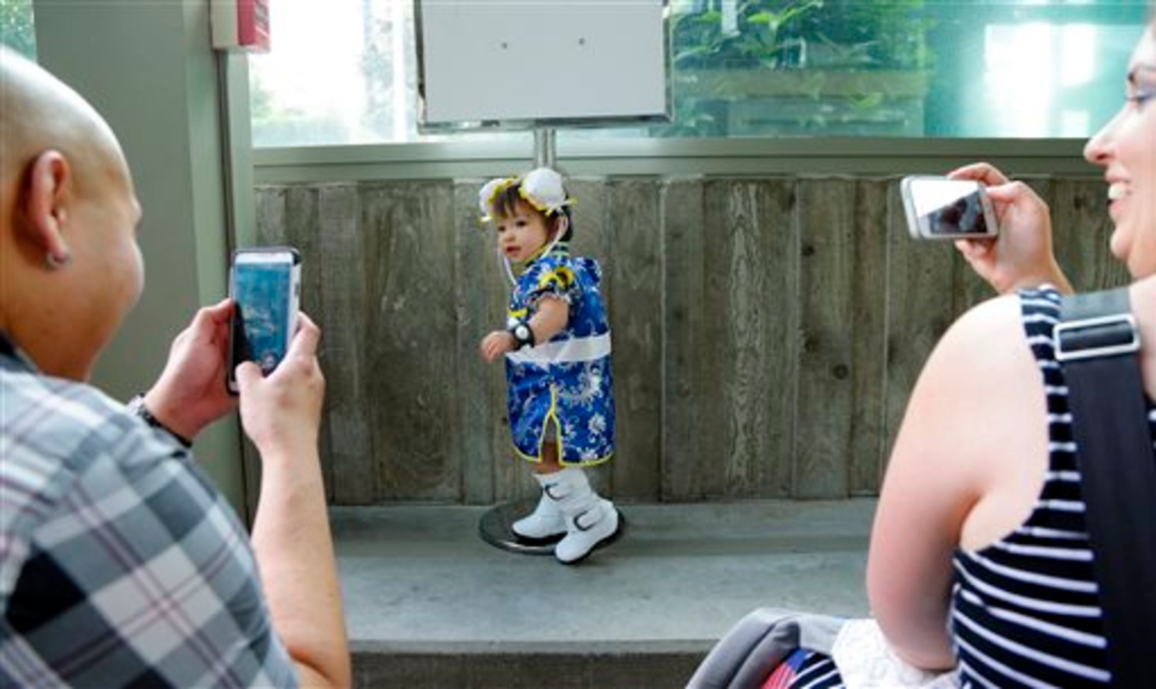 Lois, 13 months, is photographed by her mother Amanda, right, as she shows off her costume of Chun-Li, from the video game Street Fighter, Friday, Aug. 29, 2014, at the Penny Arcade Expo, a fan-centric celebration of gaming in Seattle. The event is expected to be attended by roughly 85,000 gamers and will include concerts, game tournaments and previews of upcoming titles. (AP Photo/Ted S. Warren)