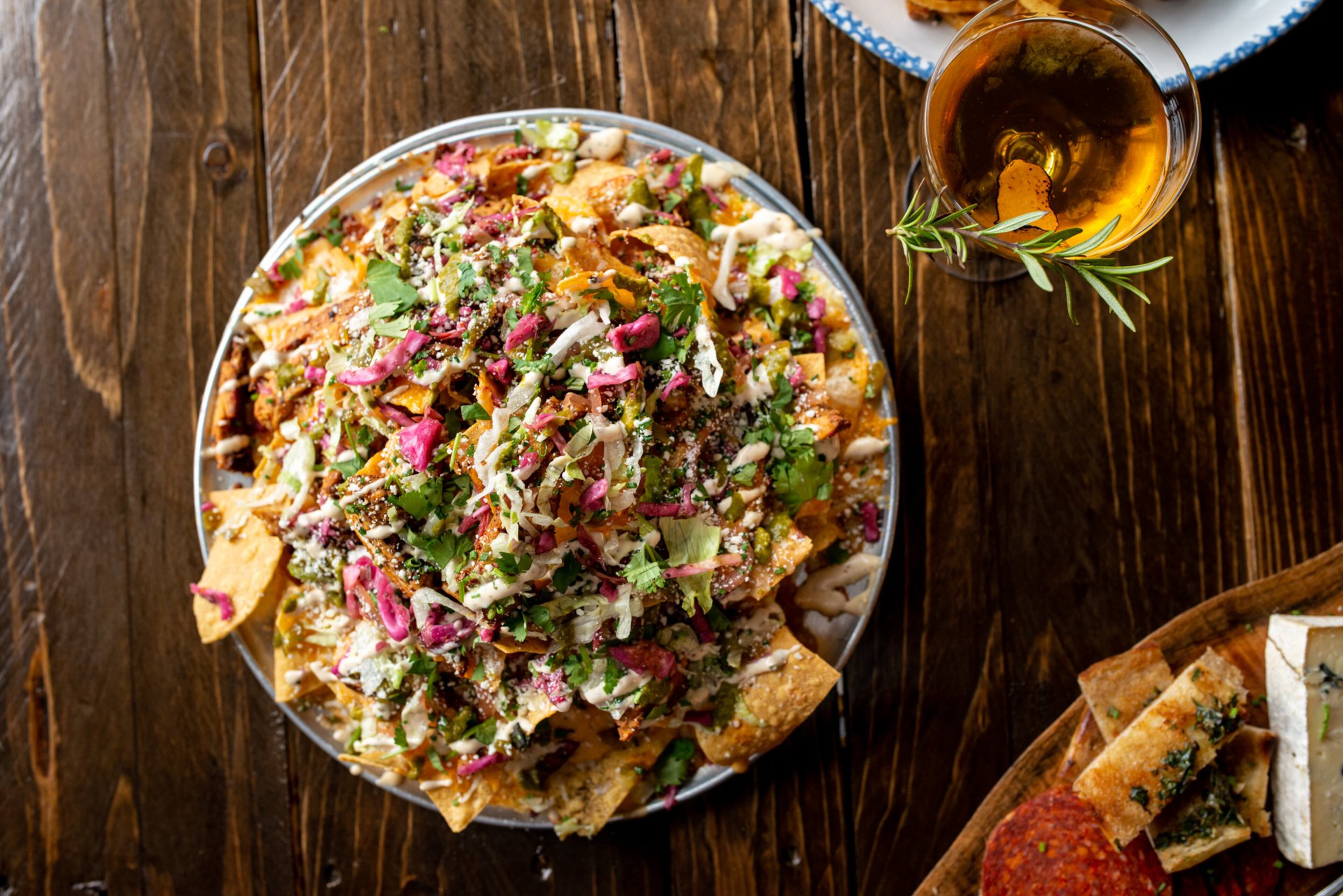 Nachos with chicken, jack cheese, salsa, cilantro, diced jalapeno, lettuce, creme, and diced red onions. Photo credit- Mia Yakel.
