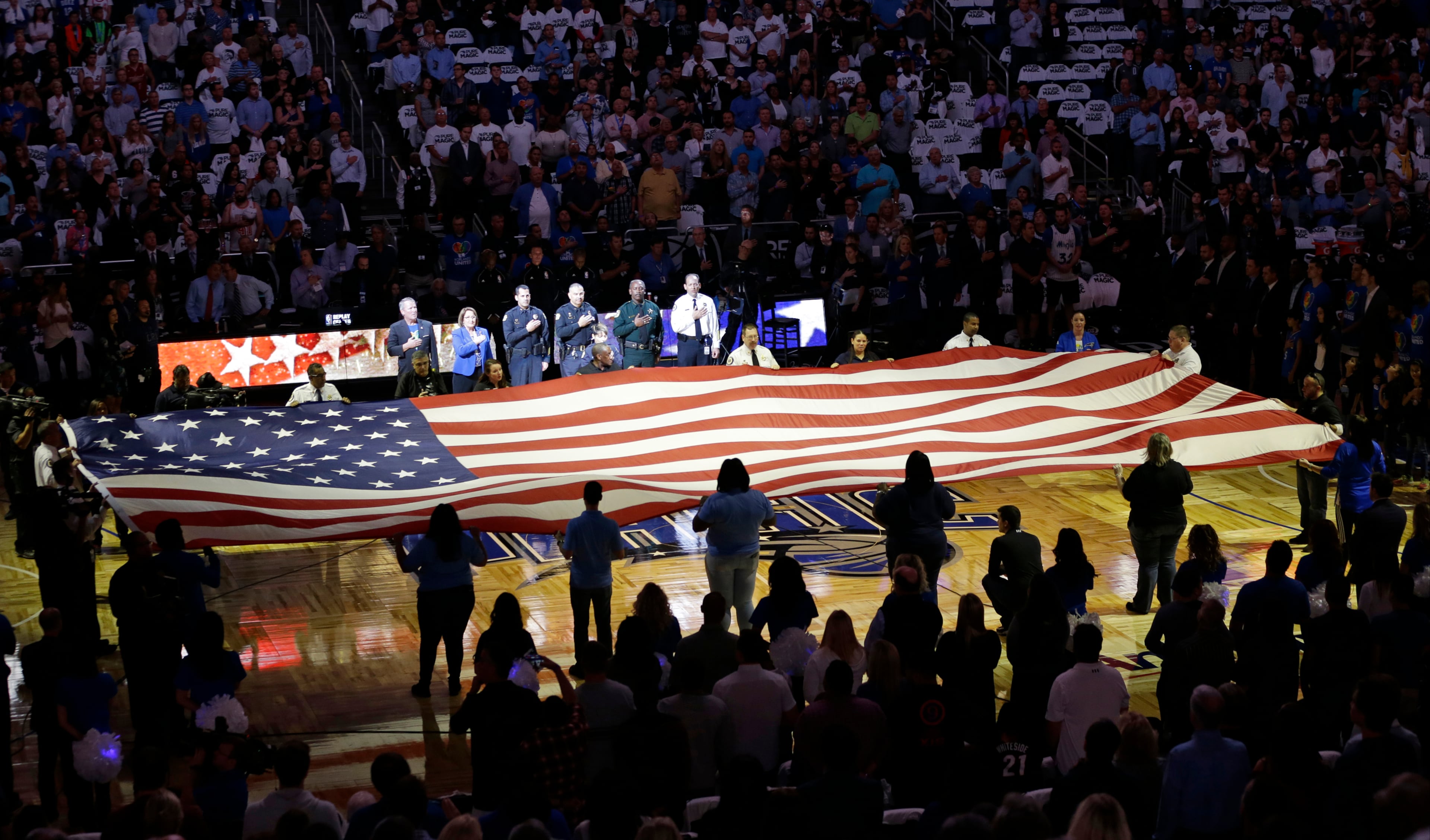First responders hold a flag on the court as the national anthem is played during a tribute to the victims of the Pulse nightclub shooting prior to an NBA basketball game between the Orlando Magic and the Miami Heat, Wednesday, Oct. 26, 2016, in Orlando, Fla. (AP Photo/John Raoux)