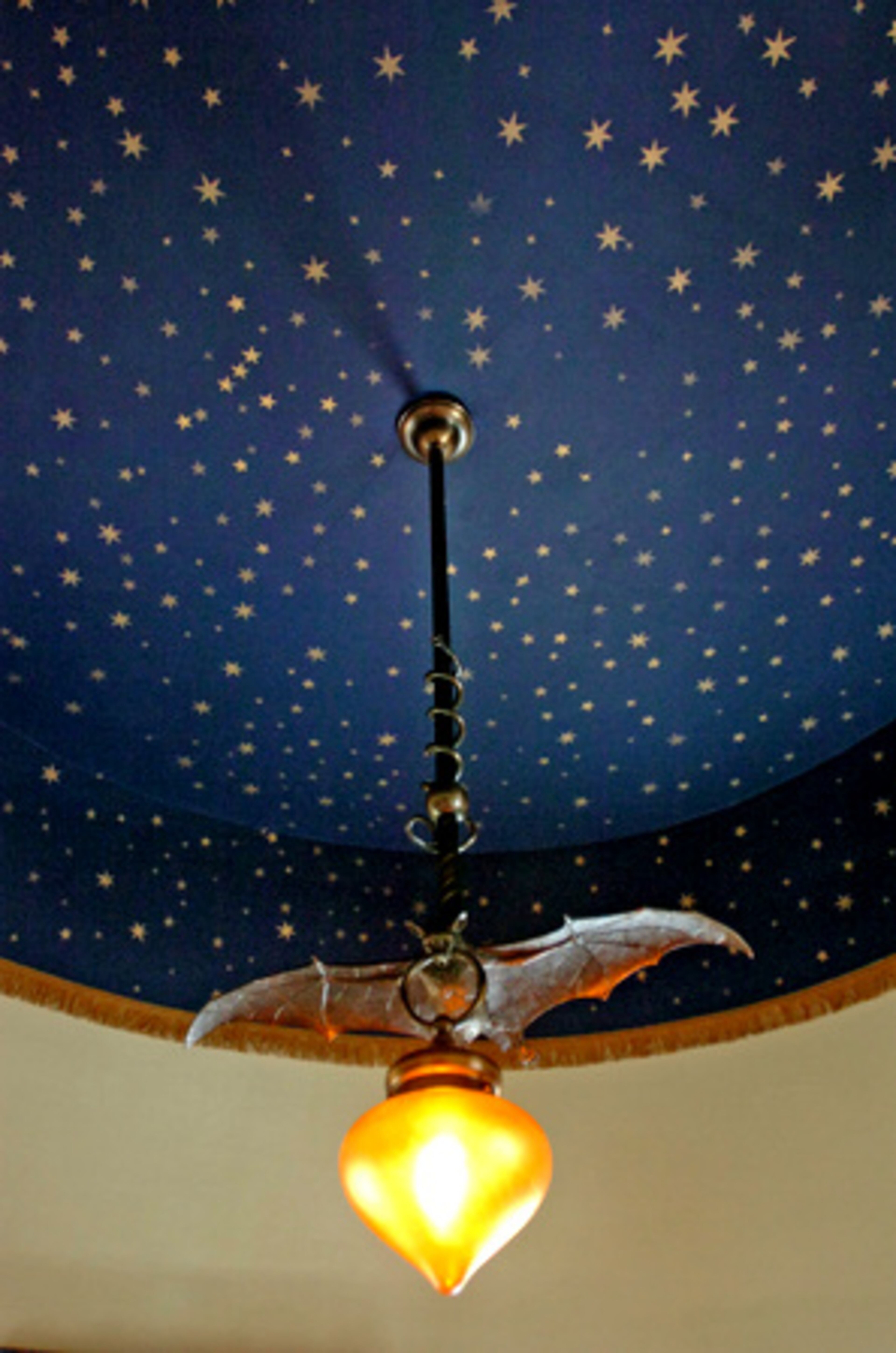 This is a detail photo of the sitting area in the turret on the third floor. The homeowners stenciled stars on the ceiling and added fringe. The bat chandelier came from Rejuvenation.