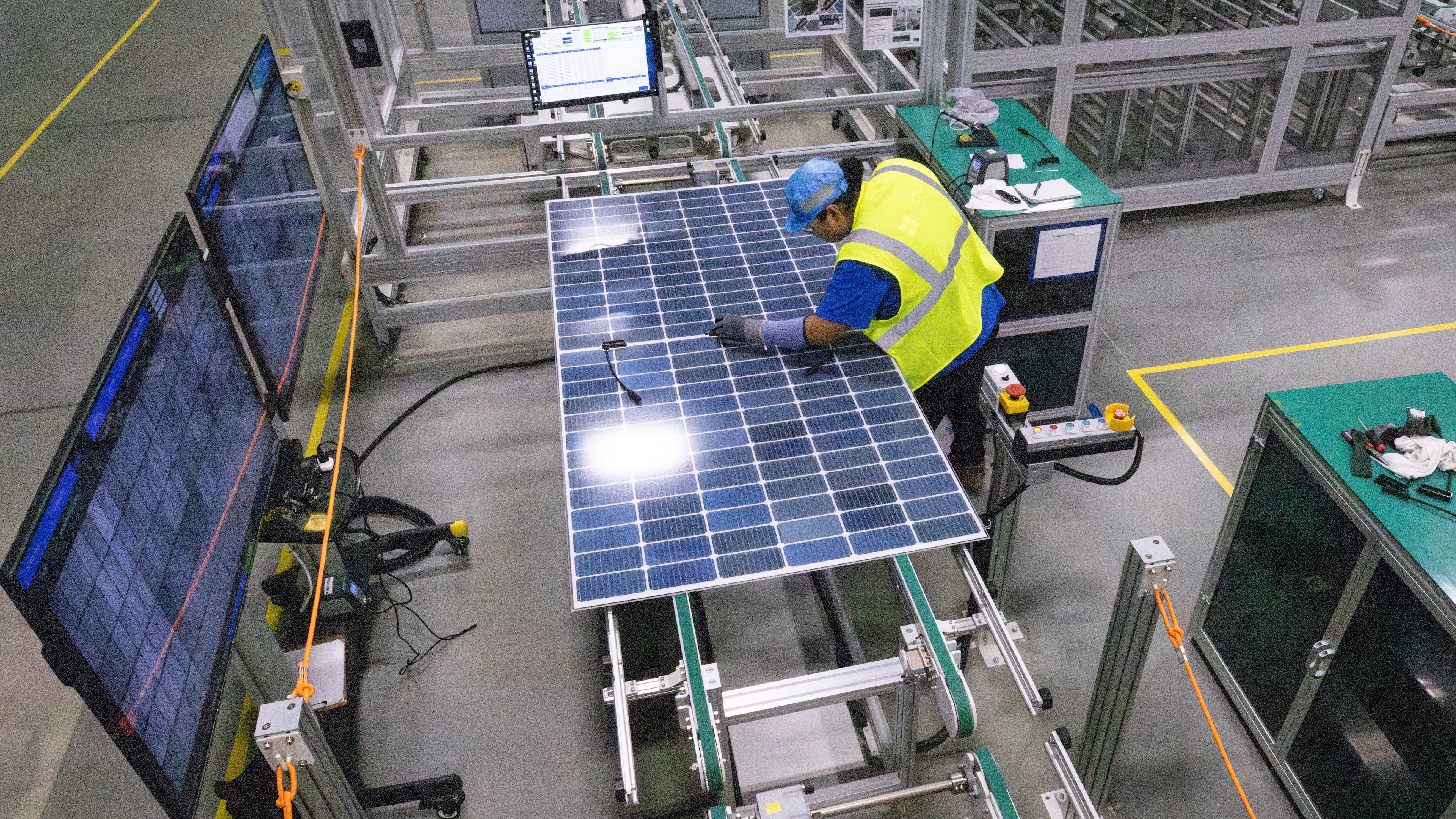 A worker makes a visual inspection of one of the solar panels as it moves through the automated assembly line at the Qcells module production facility in Cartersville on Tuesday, April 2, 2024. (Steve Schaefer/steve.schaefer@ajc.com)