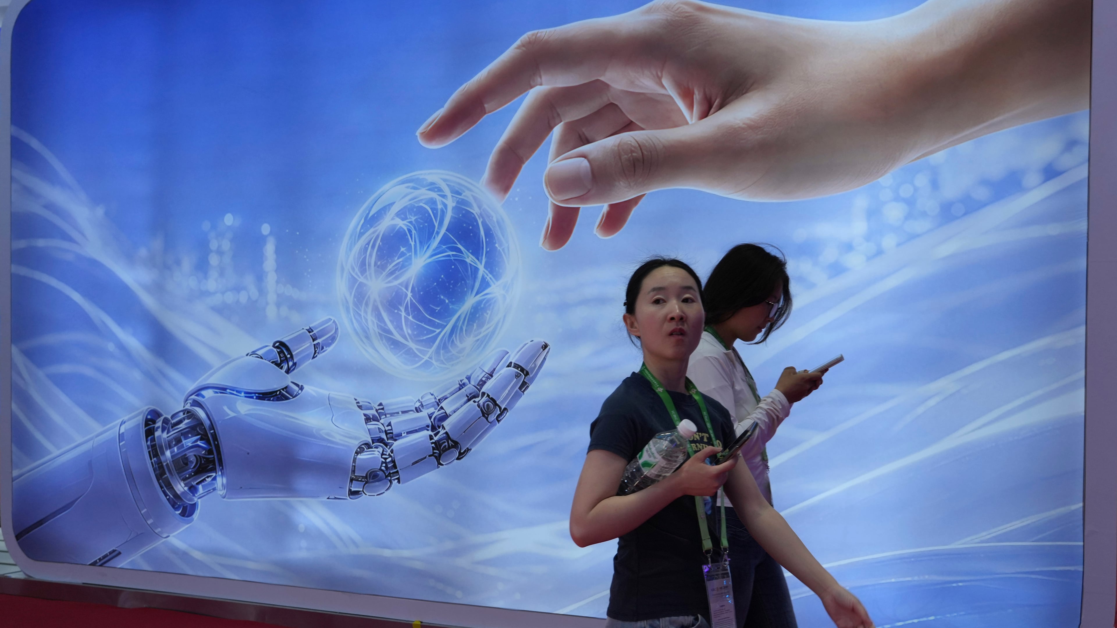 Visitors walk past a display depicting artificial intelligence and a human hand at the China International Supply Chain Expo in Beijing on Monday, June 22, 2026. (AP Photo/Ng Han Guan)