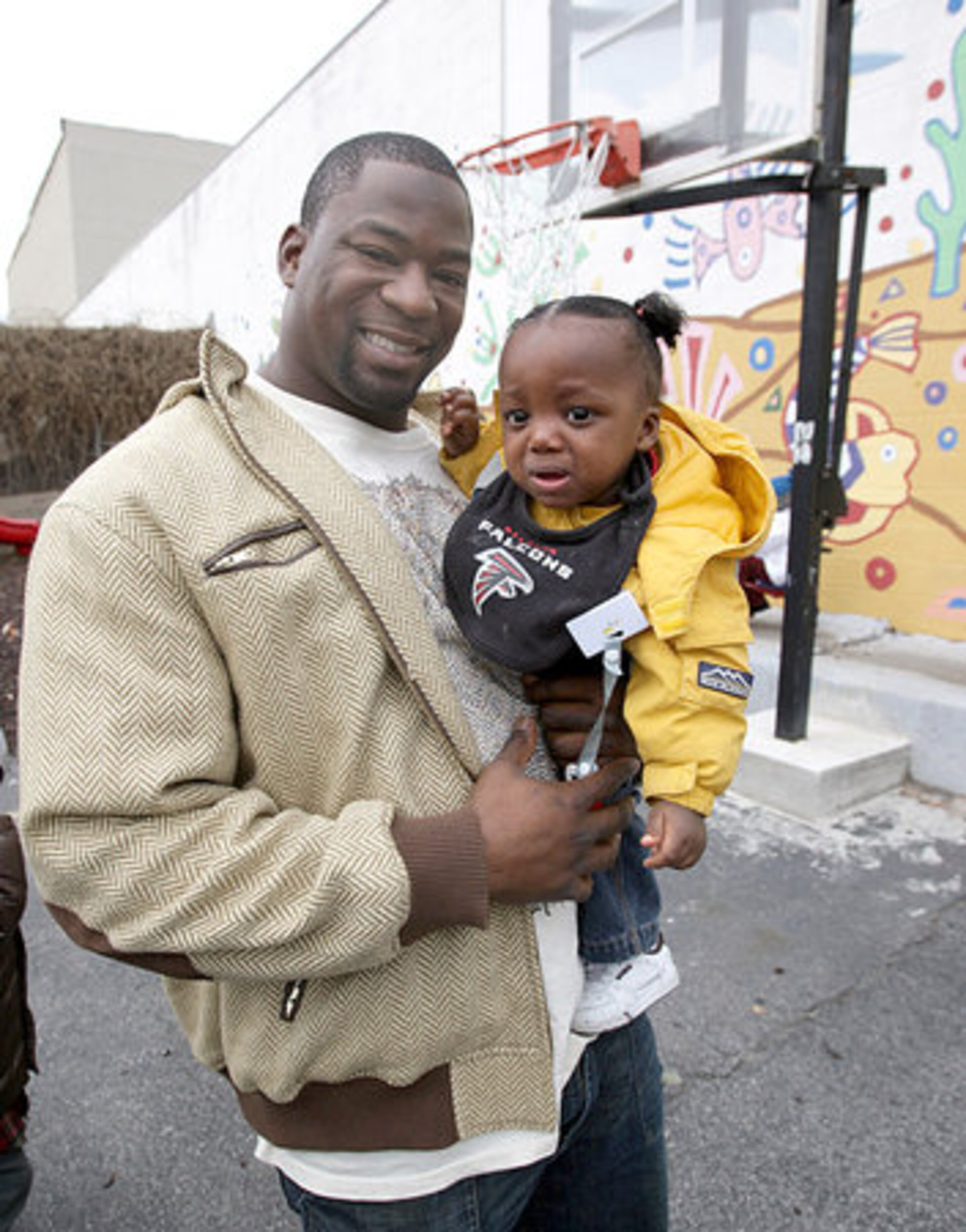 Davis holds 2-year-old Falcon fan Aaliyah Cook. The center offers day care and medical services for children, summer camps and activities both educational and recreational.