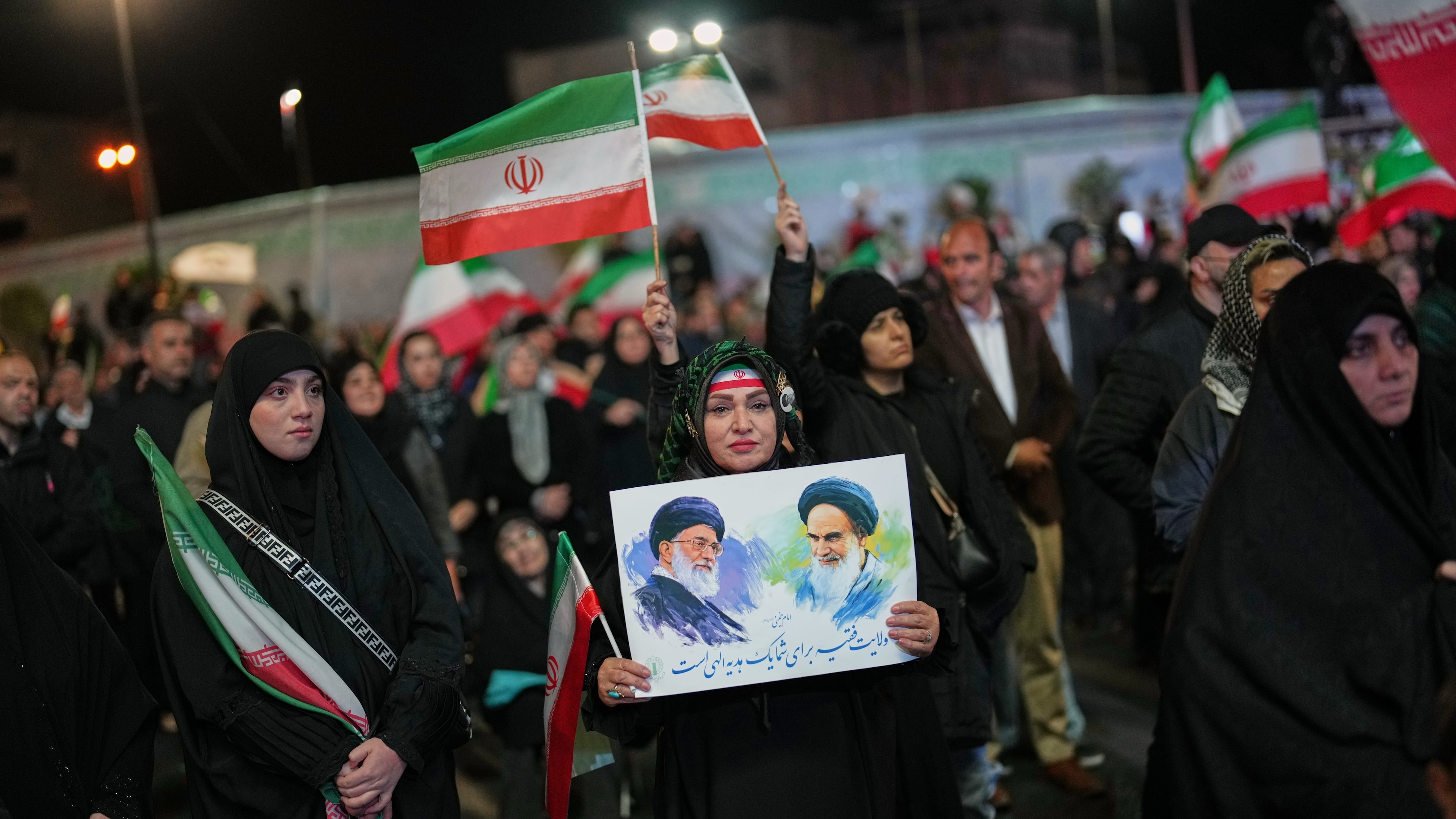 A woman holds a poster depicting the late Iran’s Supreme Leader Ayatollah Ali Khamenei, left, and the late revolutionary founder Ayatollah Ruhollah Khomeini during a pro-government gathering in a square in Tehran, Iran, Sunday, April 5, 2026. (AP Photo/Francisco Seco)