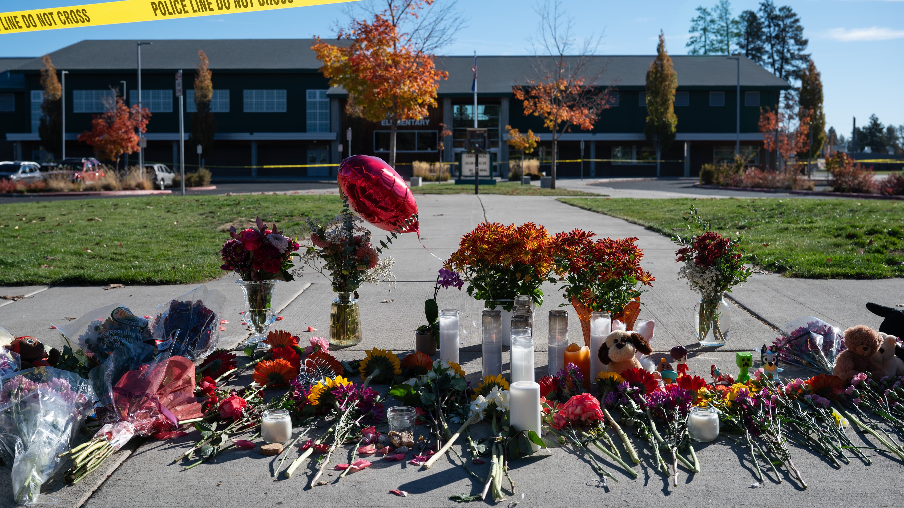 Flowers and candles are seen at a makeshift memorial outside Silver Rail Elementary in Bend, Ore., Friday, Oct. 16, 2026, a day after a deadly shooting. (AP Photo/Joe Kline)
