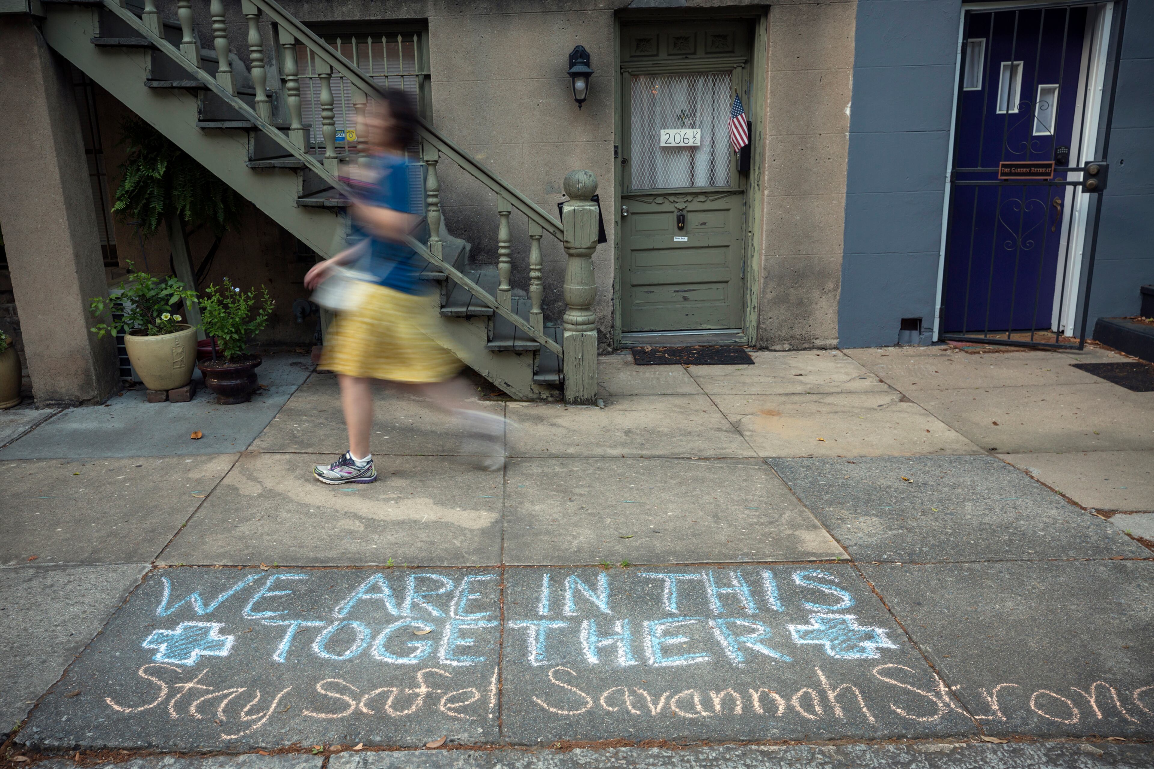 SAVANNAH, GA - APRIL 6, 2020: A Savannah resident walks past a sidewalk caulk message with an encouraging tone. Many of the streets and squares in the Historic Downtown Neighborhood are nearly empty since the City of Savannah issued a shelter-in-place directive in March. (Stephen B. Morton for The Atlanta Journal-Constitution)