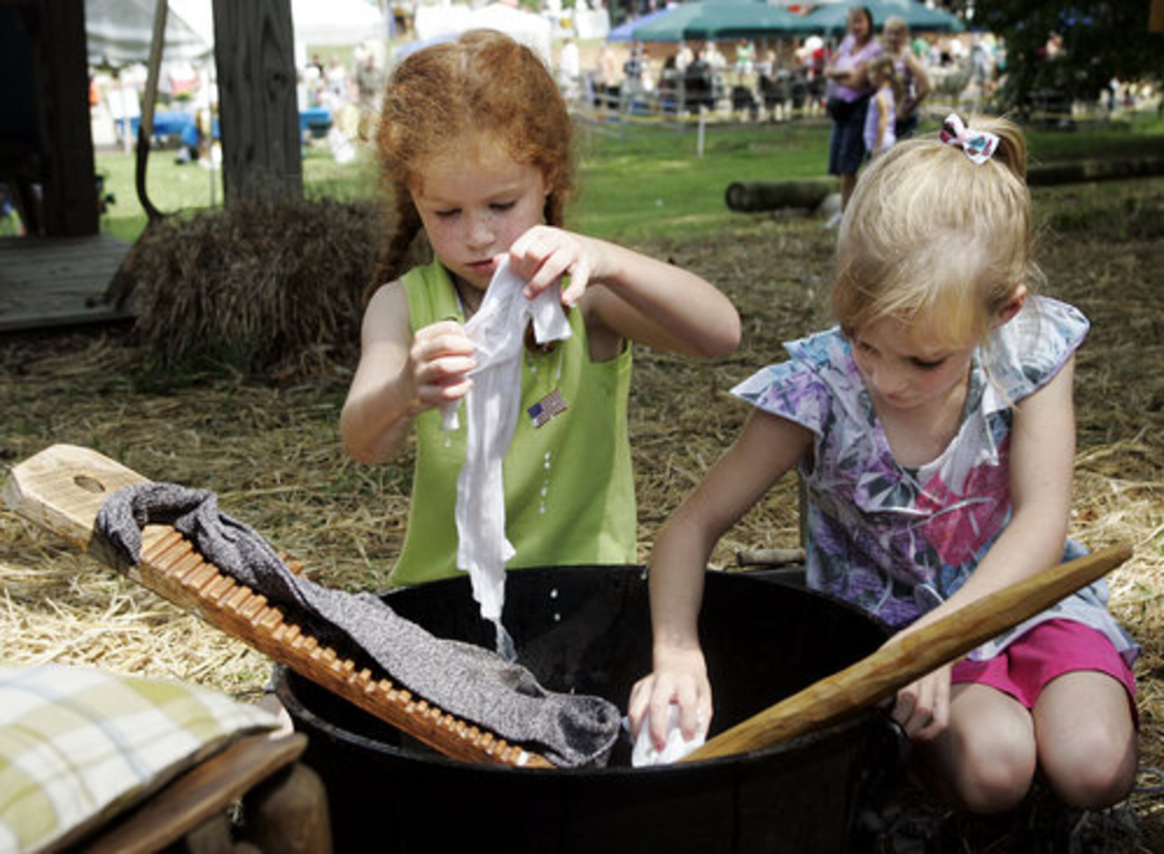 Kathryn Peyton and Maddie Loventz, both age 5, get an idea of what cleaning clothes was like before washing machines.