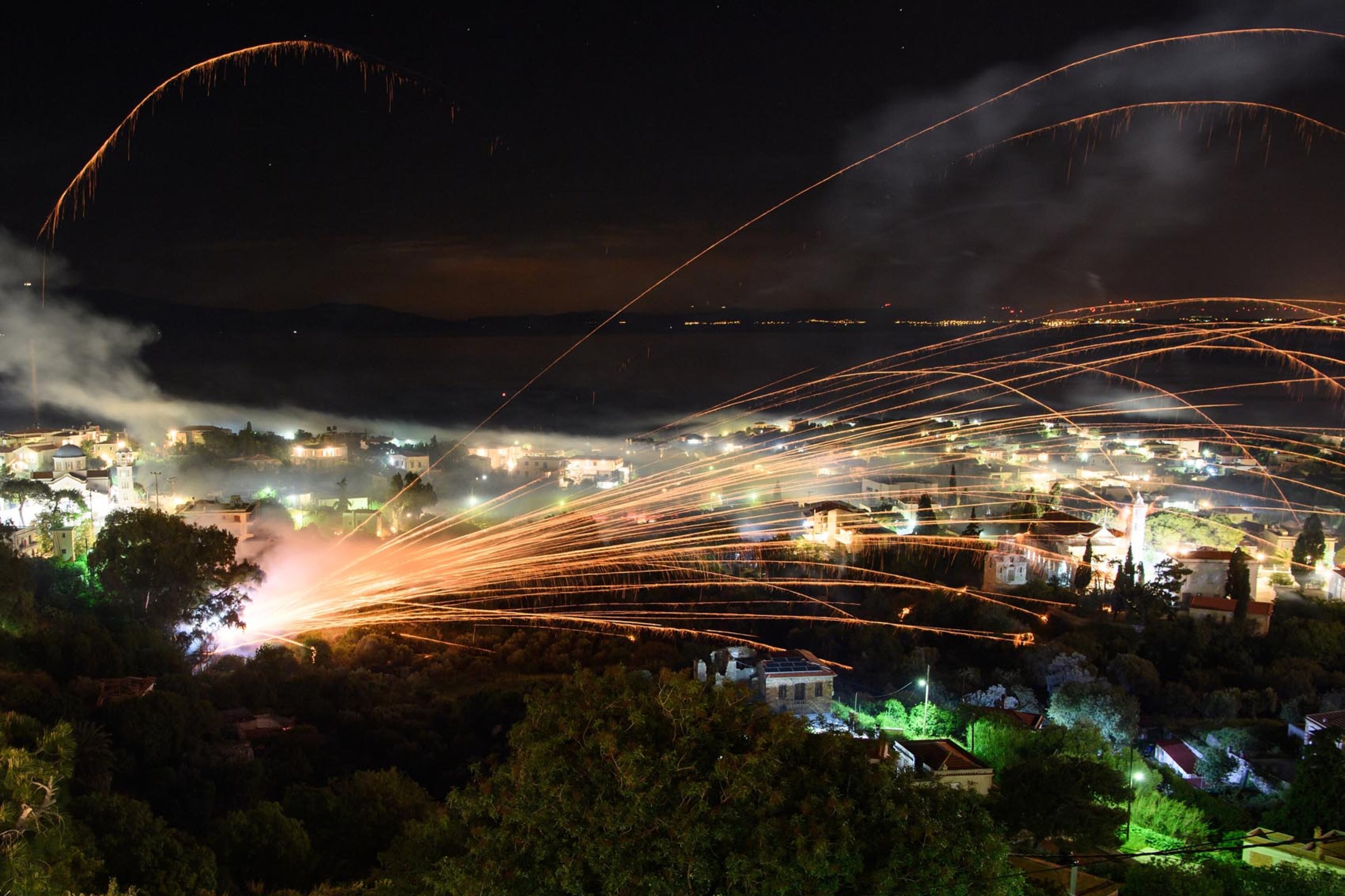 CHIOS, GREECE - APRIL 15: Rockets are fired between the Aghios Marko Church and the Panaghia Erithiani Church during the annual Rocket War, known locally as the "Rouketopolemos", on April 15, 2017 in Chios, Greece. The event takes place at Easter in the town of Vrontados, where the congregations from two rival churches launch a "rocket war", attempting to hit the bell tower of the opposing church with tens of thousands of home-made rockets. Homes in the area are forced to erect temporary protective fencing to prevent damage to their property while tourists come from all over the world to watch the spectacle. (Photo by Leon Neal/Getty Images)