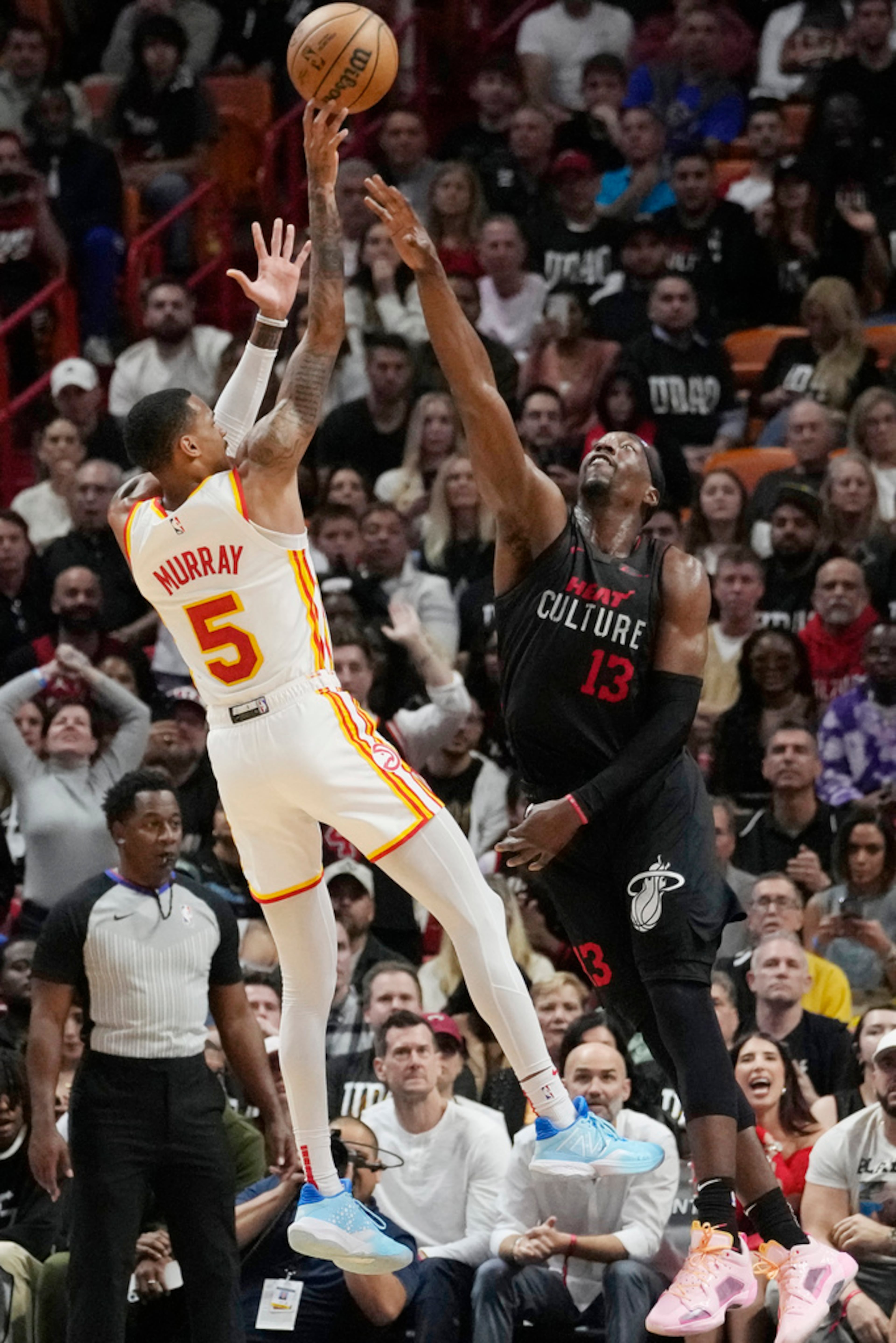 Atlanta Hawks guard Dejounte Murray (5) aims a three point shot as Miami Heat center Bam Adebayo (13) defends during the second half of an NBA basketball game, Friday, Jan. 19, 2024, in Miami. (AP Photo/Marta Lavandier)