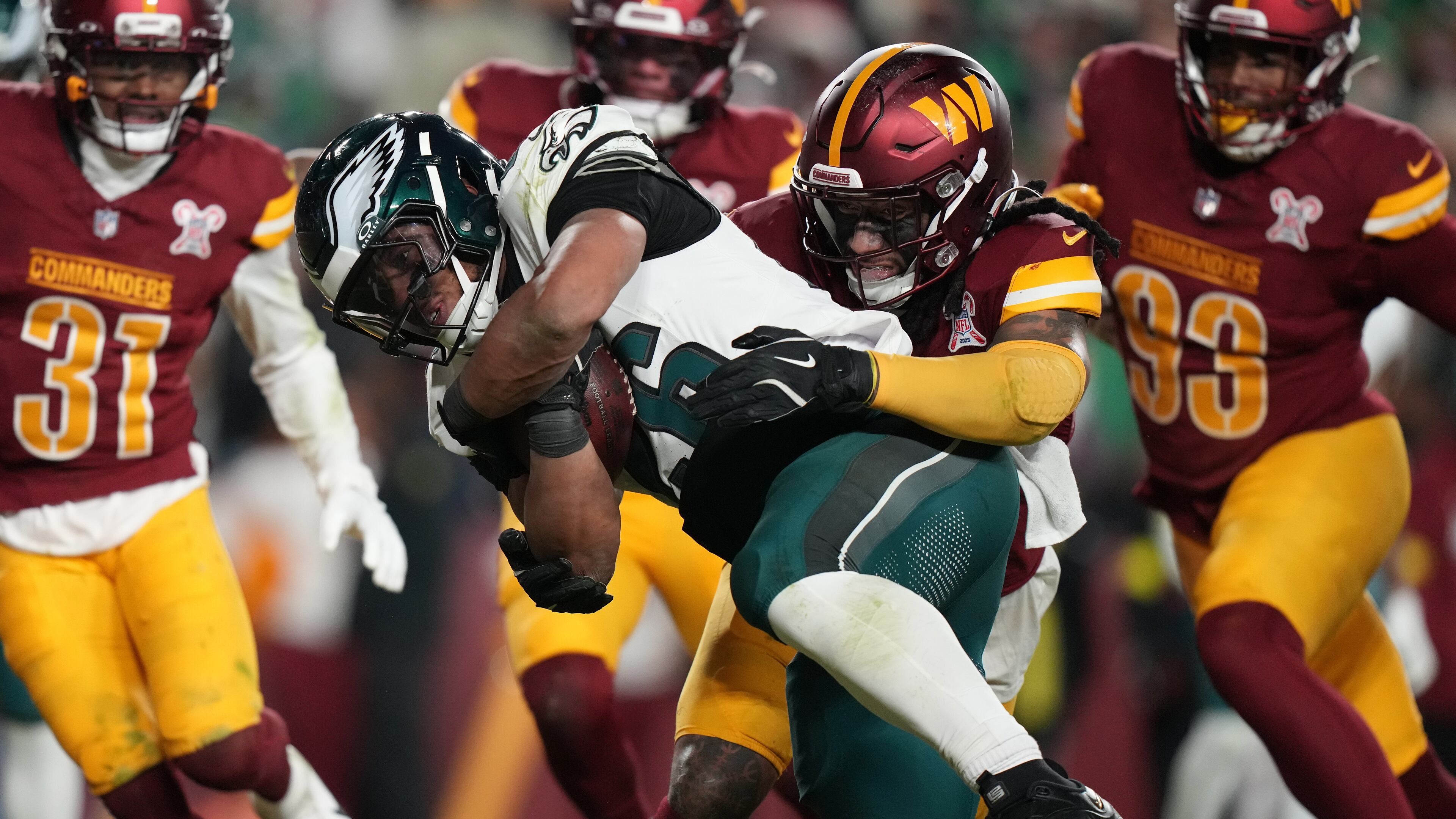 Philadelphia Eagles running back Saquon Barkley, center left, runs for a touchdown against Washington Commanders cornerback Noah Igbinoghene, center right, during the second half of an NFL football game, Saturday, Dec. 20, 2025, in Landover, Md. (AP Photo/Stephanie Scarbrough)