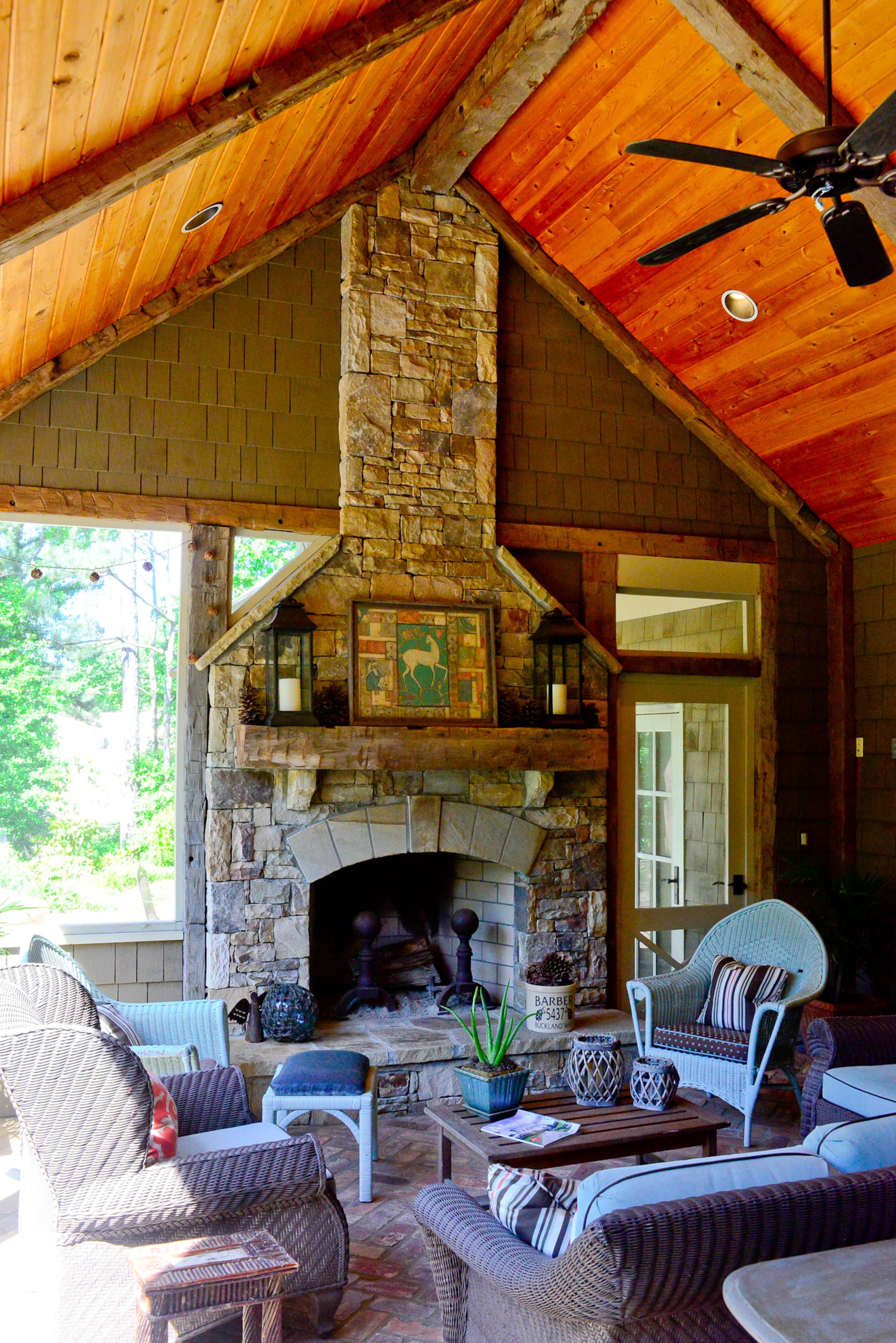 The screened porch boasts a vaulted ceiling made of hand-hewn oak beams from an Ohio barn and a stacked stone fireplace. The wicker furniture has been purchased, mostly from Scott Antique Market, over the years.