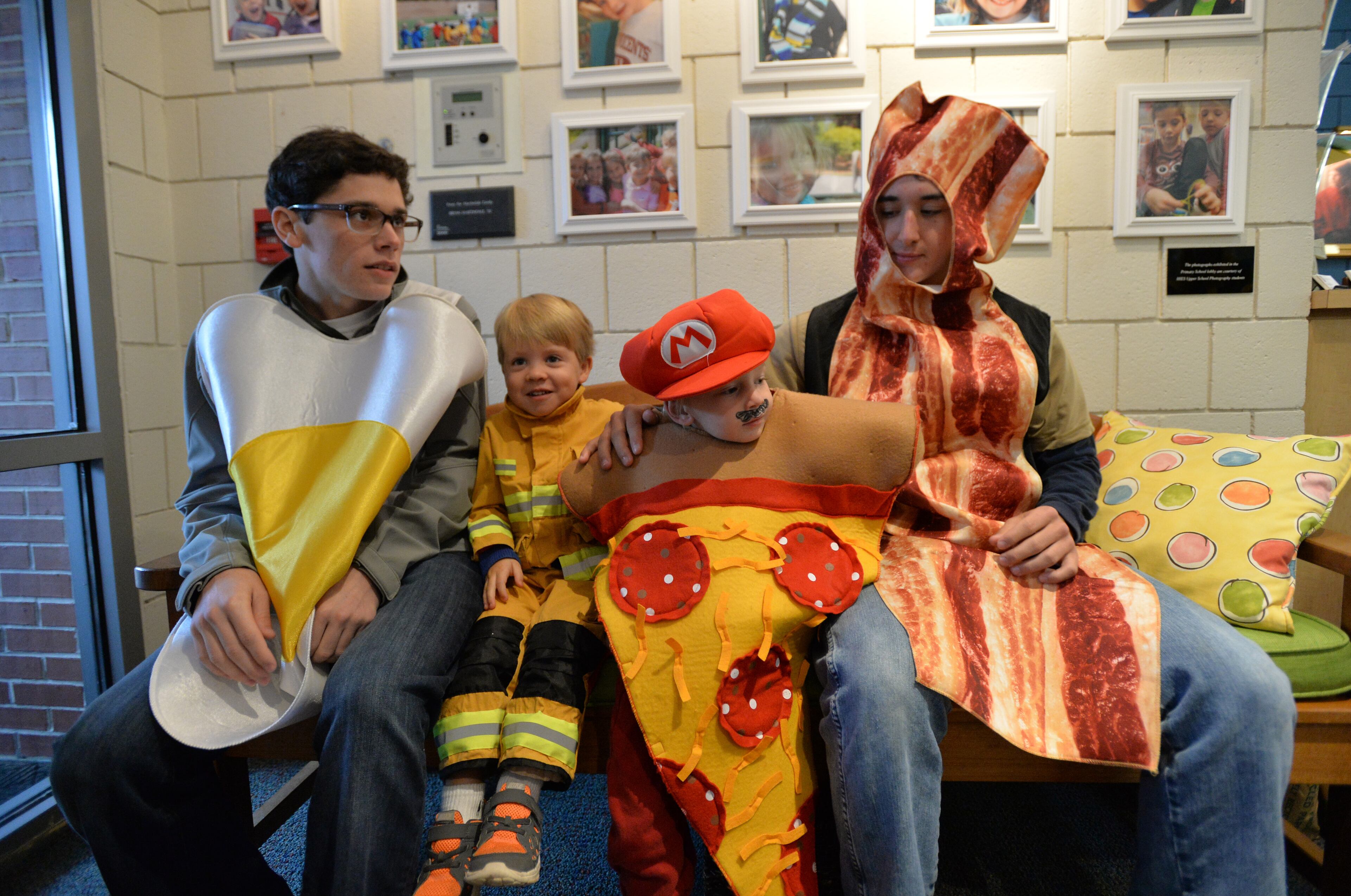 Seniors Joe Charron (left) and Graham Thomas sit with preschoolers Hudson Downs (second from left) and Joel Glaze as they wait before the Holy Innocents' Episcopal School's annual Halloween Parade in Atlanta on Friday, October 31, 2014. This year was the 46th year for the parade at the school founded in 1959. HYOSUB SHIN / HSHIN@AJC.COM