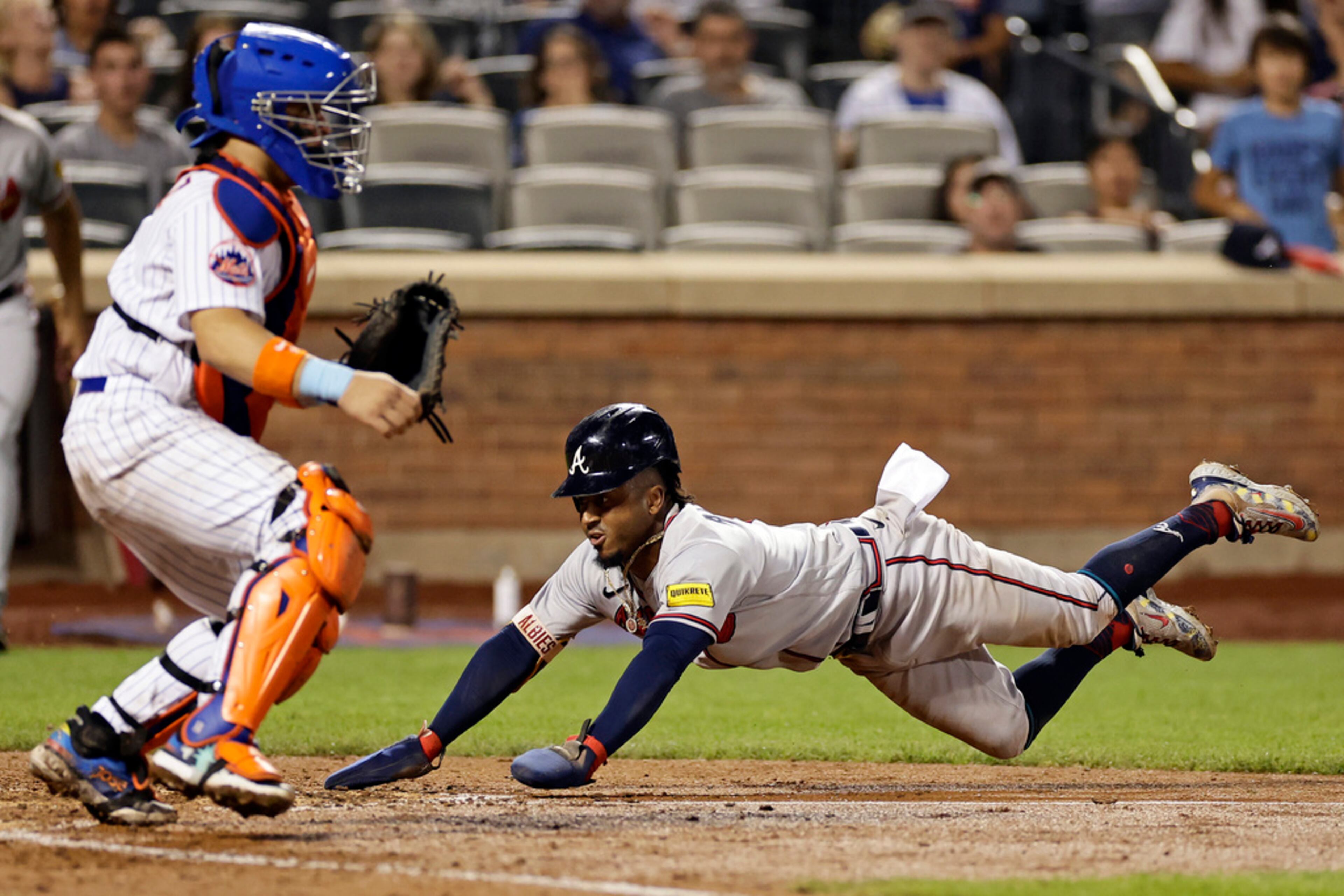 Atlanta Braves' Ozzie Albies, right, scores past New York Mets catcher Francisco Alvarez, left, after Mets' Tim Locastro was charged with a fielding error during the eighth inning in the second baseball game of a doubleheader Saturday, Aug. 12, 2023, in New York. (AP Photo/Adam Hunger)