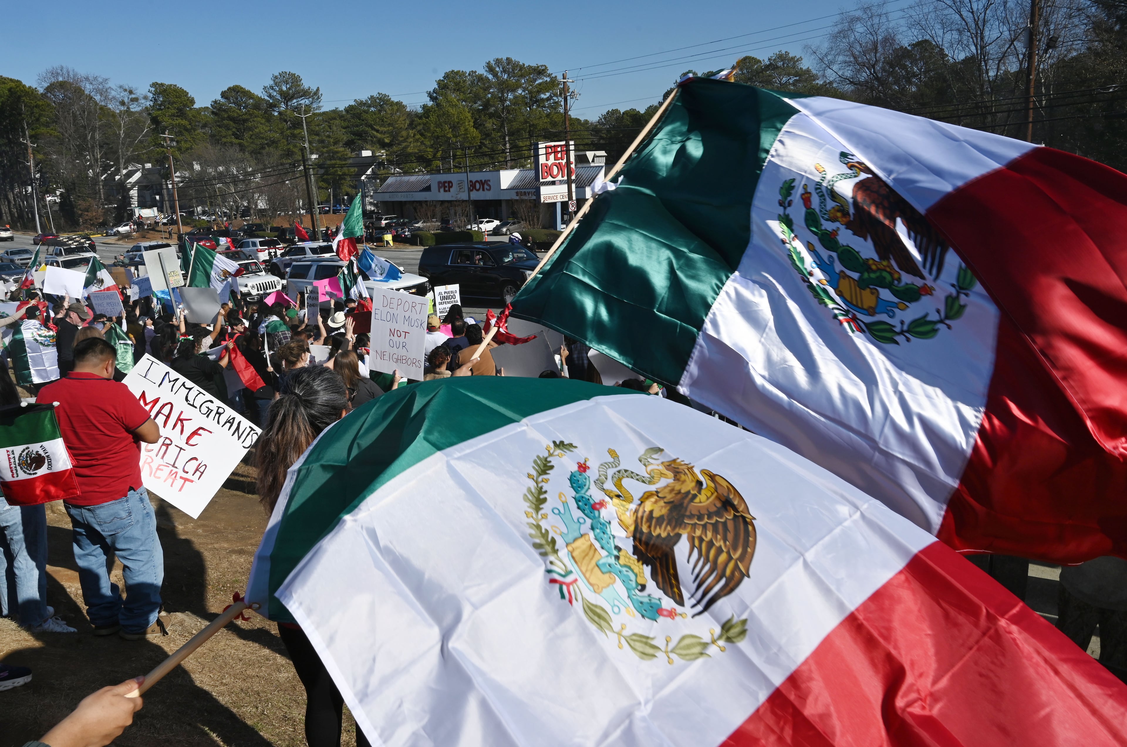Pro-immigration protesters wave flags from Mexico, Cuba, Guatemala and Puerto Rico, and carrying signs condemning deportations along both sides of the corridor in front of Plaza Fiesta, Saturday, February 1, 2025, in Atlanta. About 1,000 protesters on Saturday gathered along Buford Highway, the immigrant hub of metro Atlanta, to call for an end to the targeted operations by immigration agents that began last week. (Hyosub Shin / AJC)