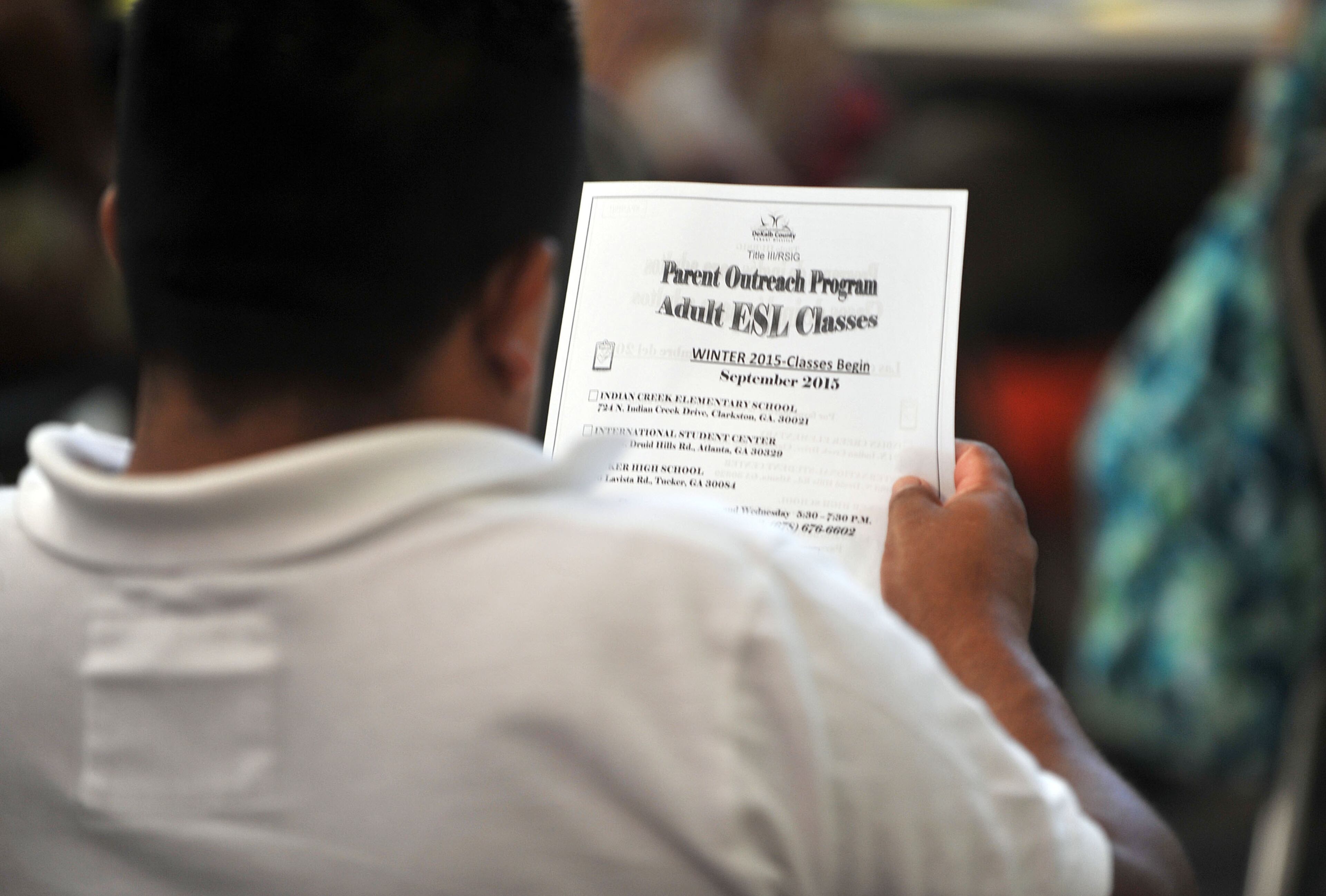 A man looks over documentation for adult English-as-a-second-language courses while waiting at the DeKalb County International Welcome Center in Stone Mountain.