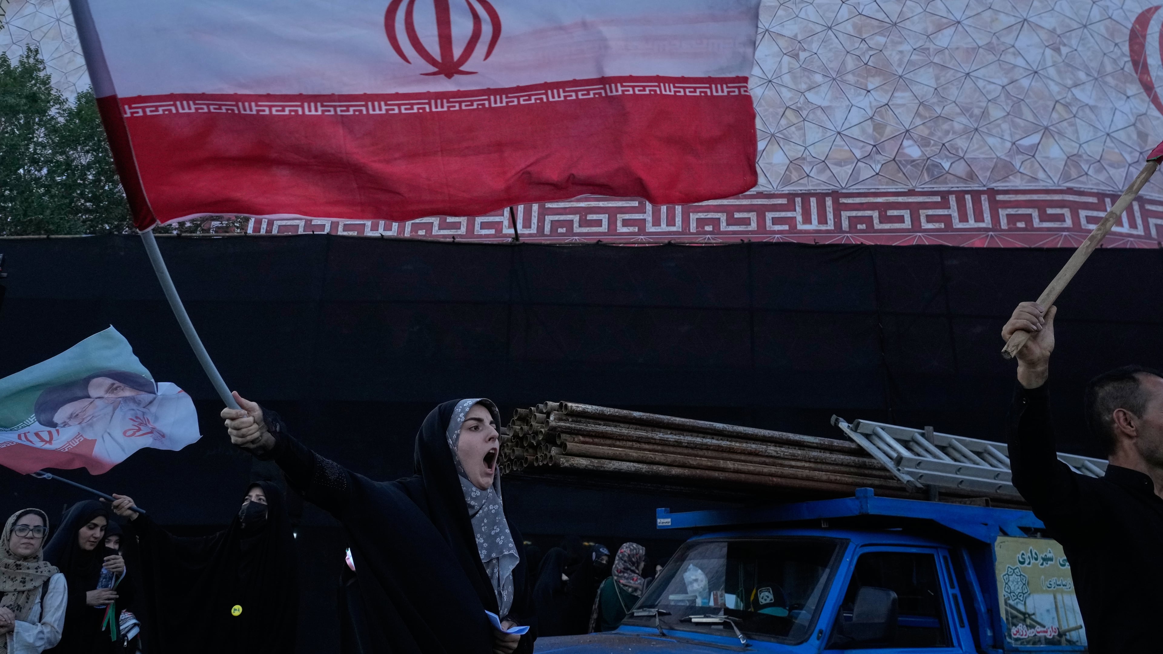 A woman waves an Iranian flags as she chants slogans against Iran and U.S. talks at the Islamic Revolution square in Tehran, Iran, Sunday, June 14, 2026. (AP Photo/Vahid Salemi)